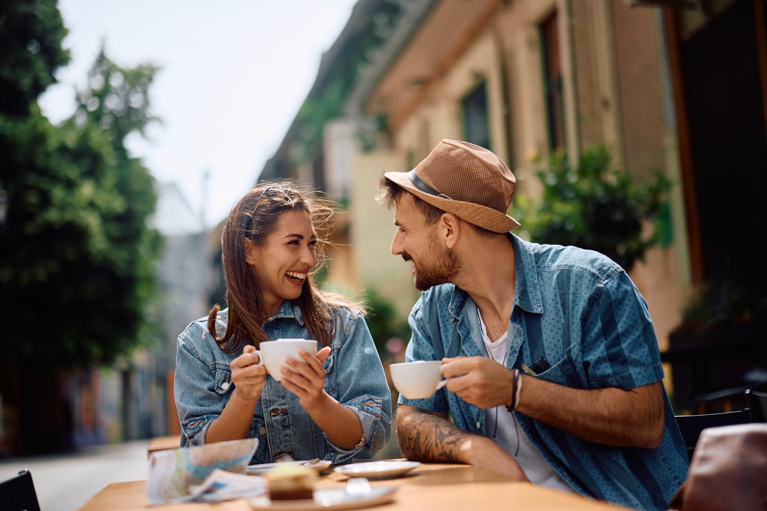 Smiling couple enjoying coffee together at an outdoor sidewalk café.