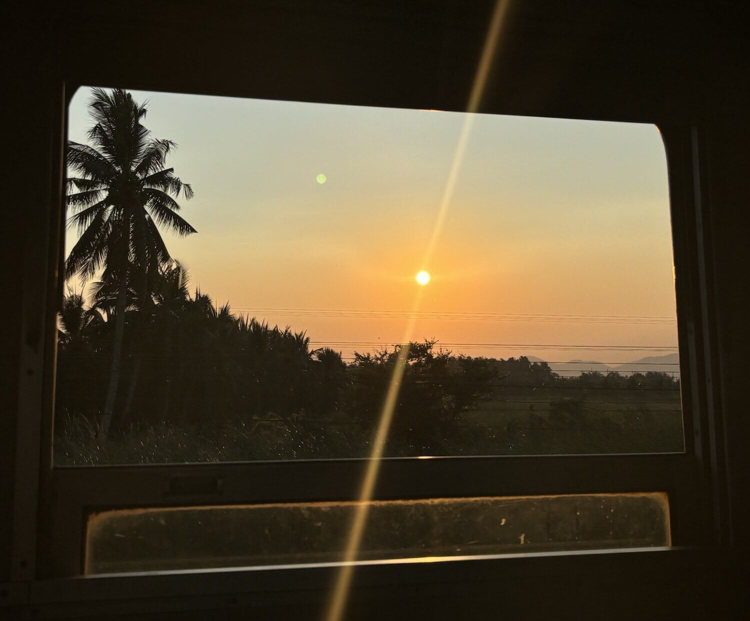 Sunset view from the window of a train in Southern Thailand.