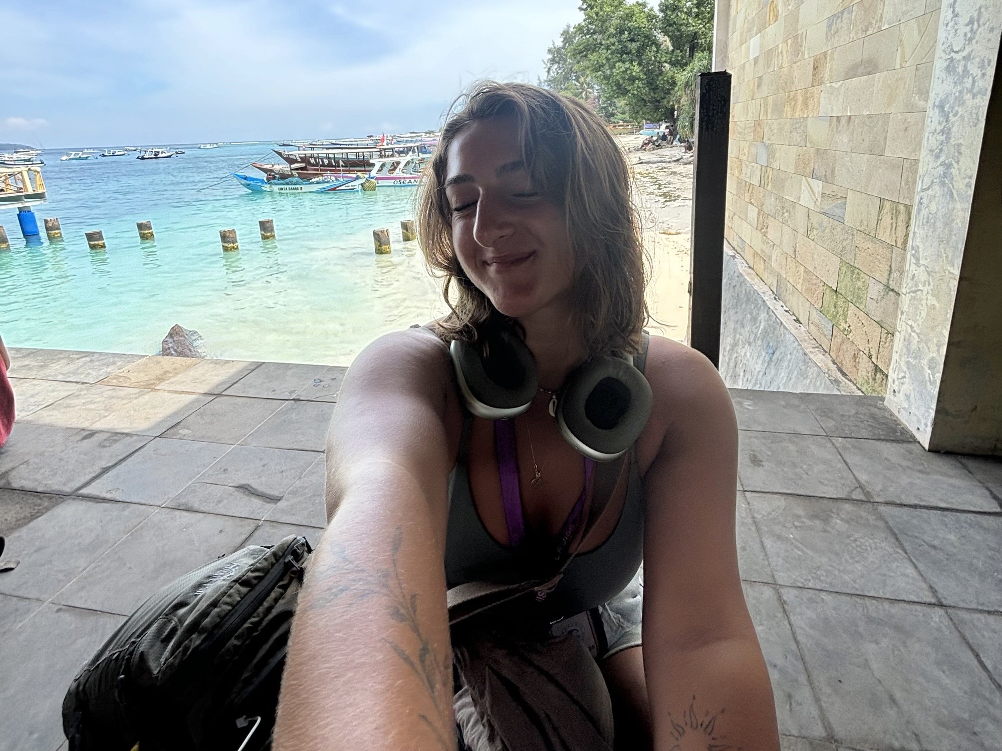 Olivia Franzman smiling by turquoise harbor waters with anchored boats in the background during her nine-month solo world trip.