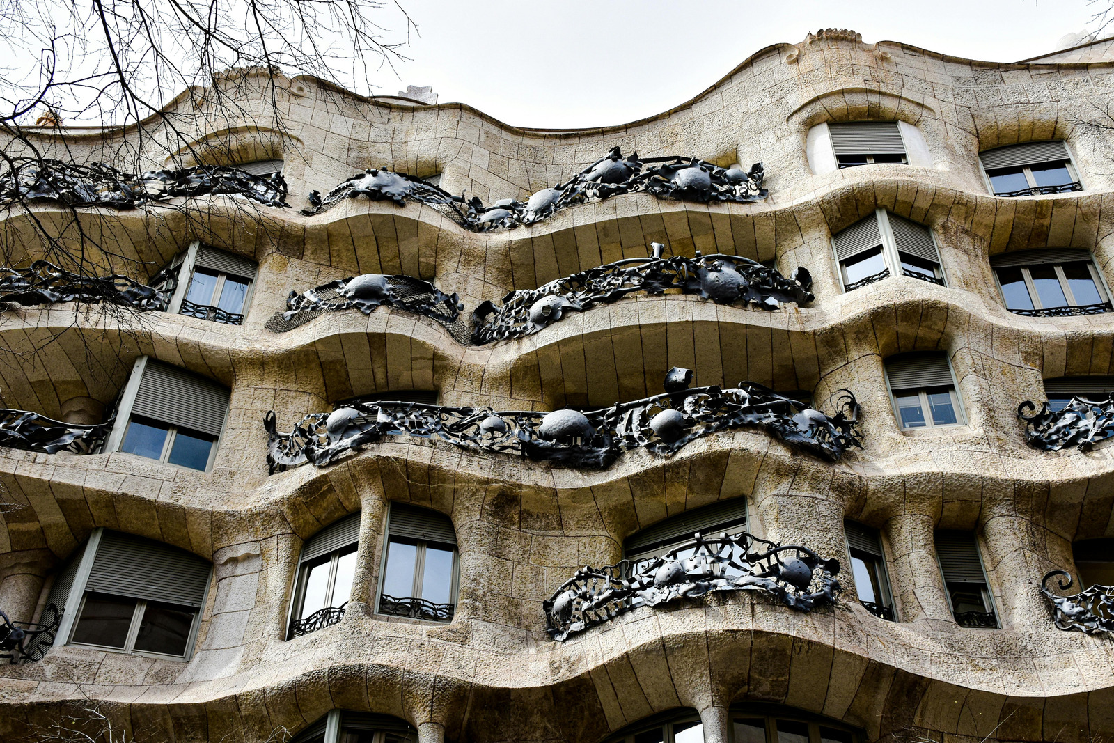 La Pedrera, or Casa Milà, in Barcelona with wavy stone facade, wrought-iron balconies, and rooftop sculpture-like chimneys.