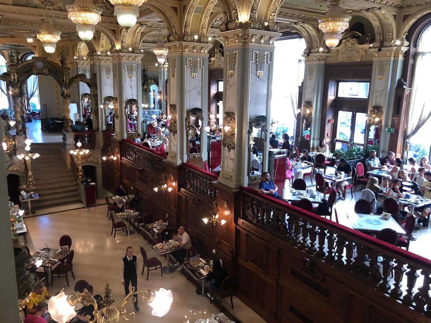 Ornate Budapest café with gilded interiors, chandeliers, and frescoed ceilings.