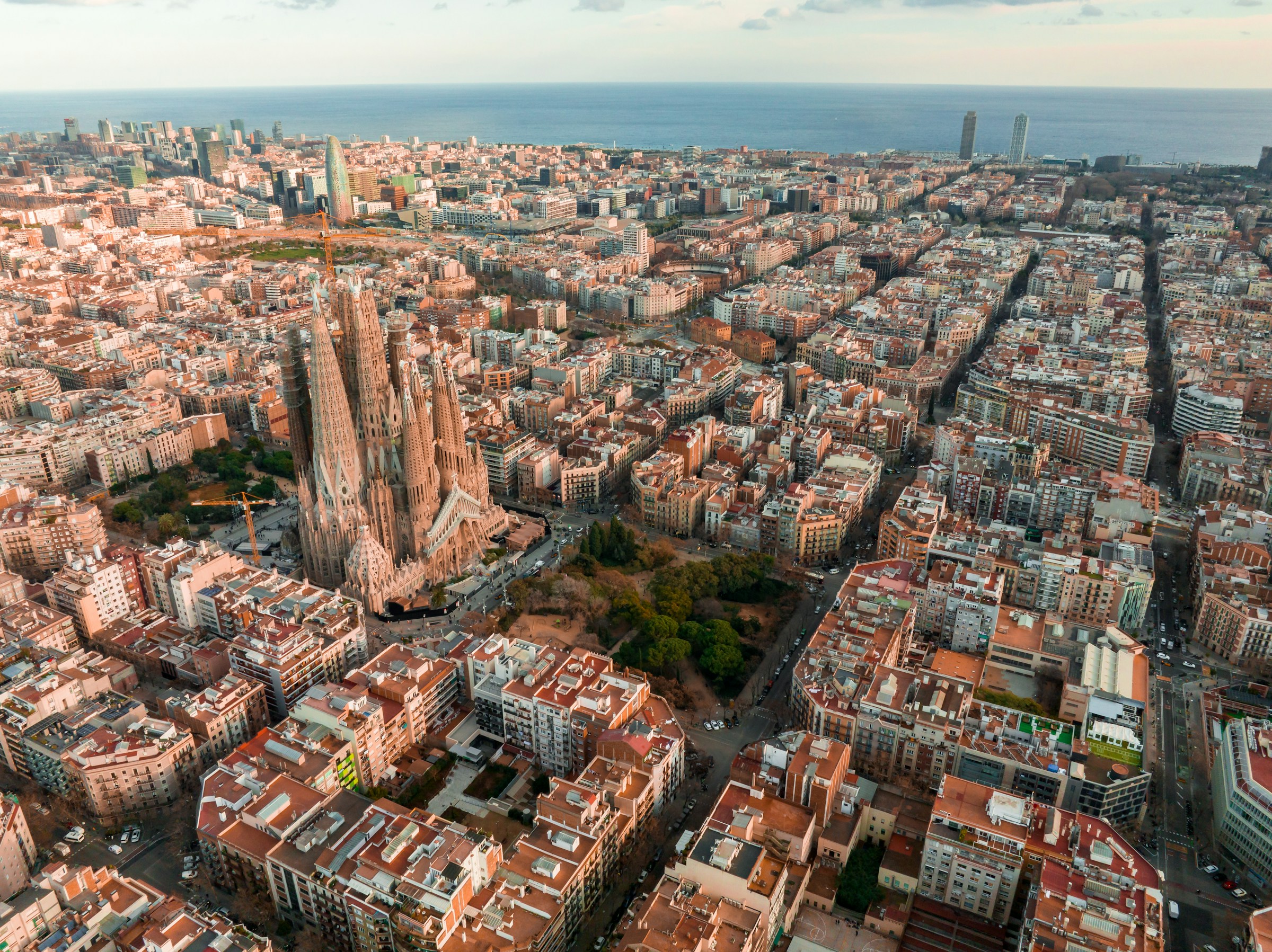 Colorful street scene in Barcelona with vibrant buildings, outdoor cafes, and lively pedestrian activity under sunny skies.