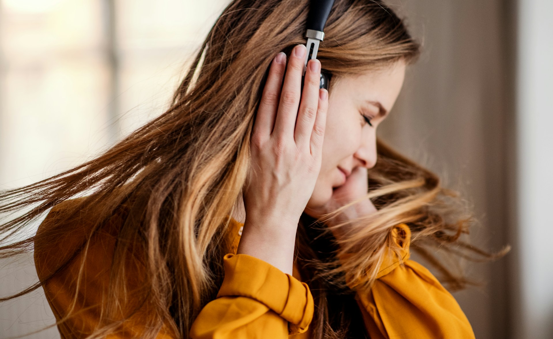 Young girl dancing and listening to music on wireless headphones