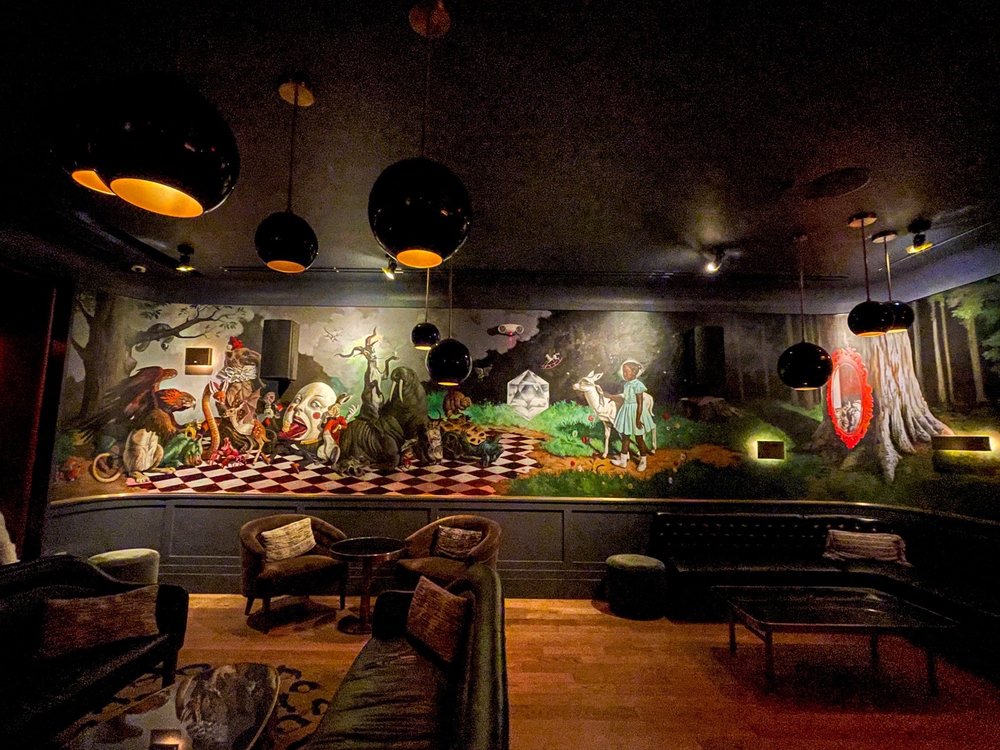 Interior of Allegory bar in Washington DC – art-filled cocktail lounge with Ruby Bridges mural and cozy dim lighting