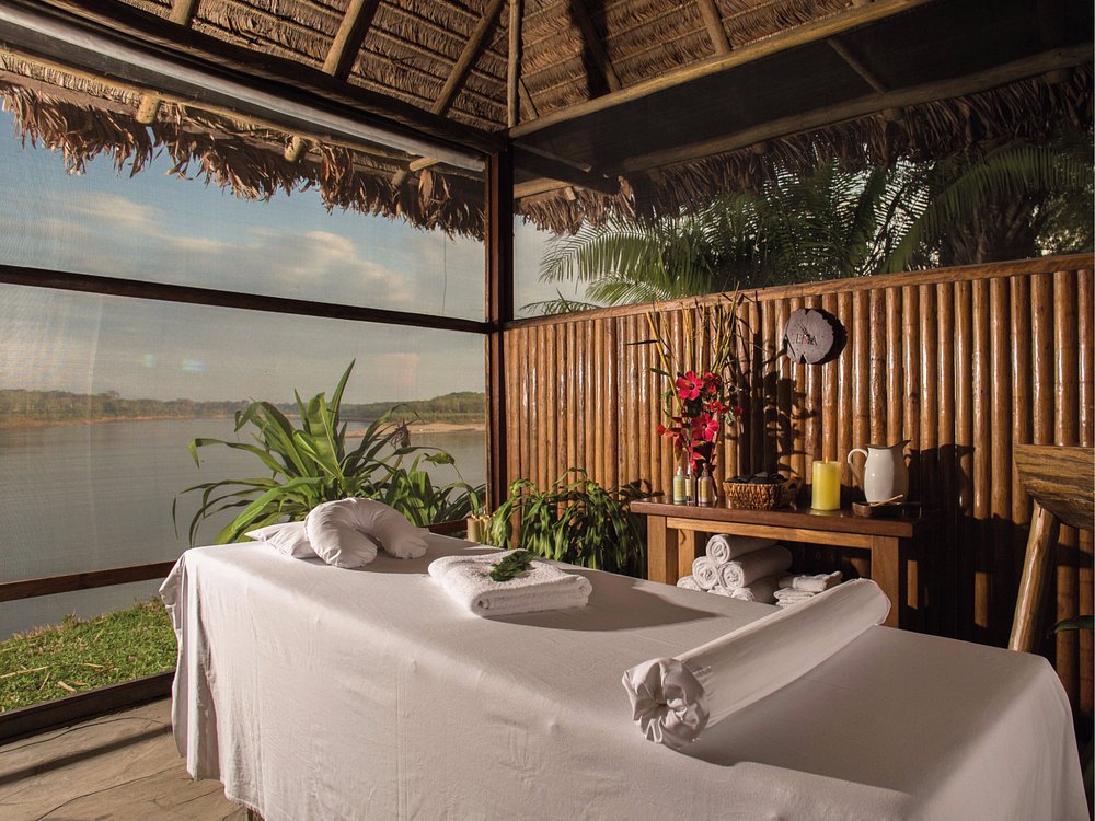 Riverside open-air spa treatment room at Inkaterra Reserva Amazonica in Peru, featuring a massage table with lush rainforest and river views