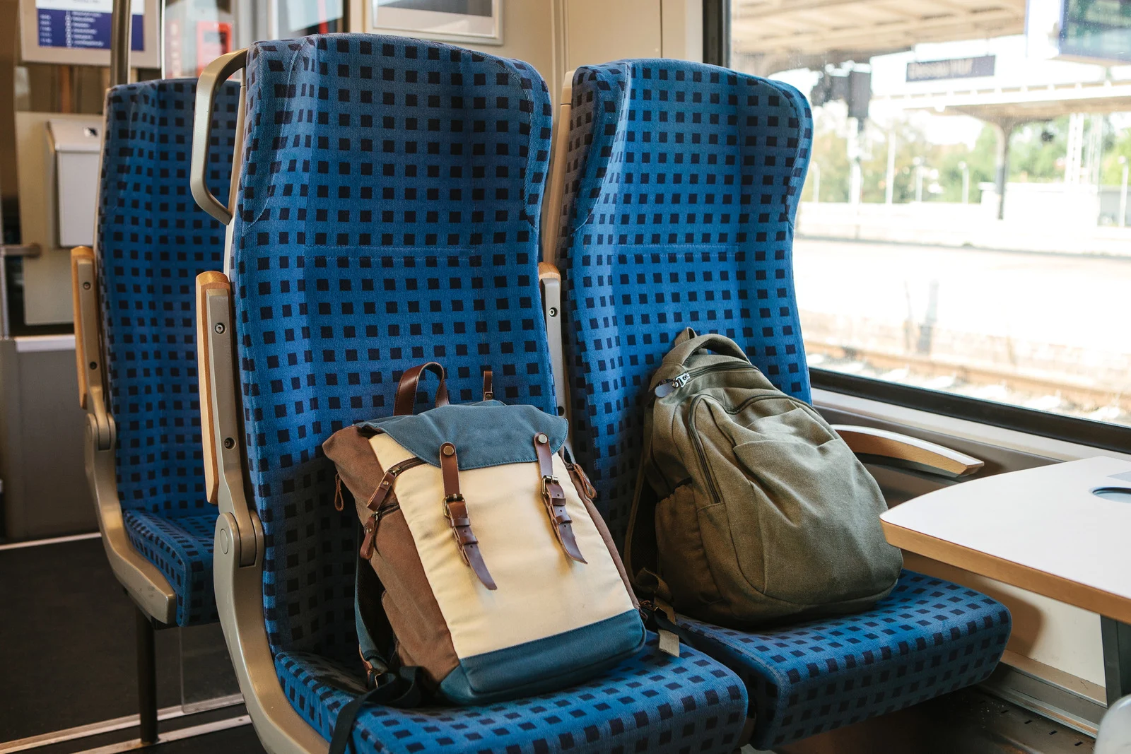 Two backpacks rest on two empty seats on a train.