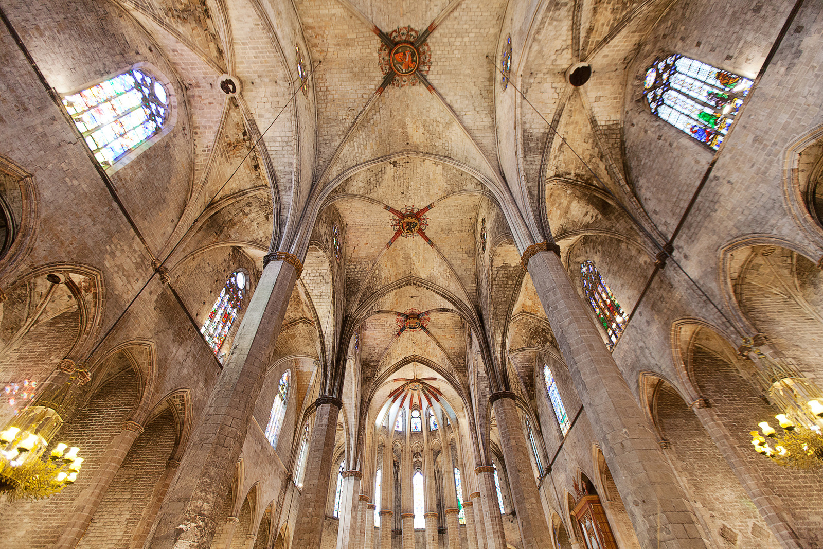 Interior of Santa Maria del Mar in Barcelona with tall stone columns, vaulted ceilings, and stained-glass windows.