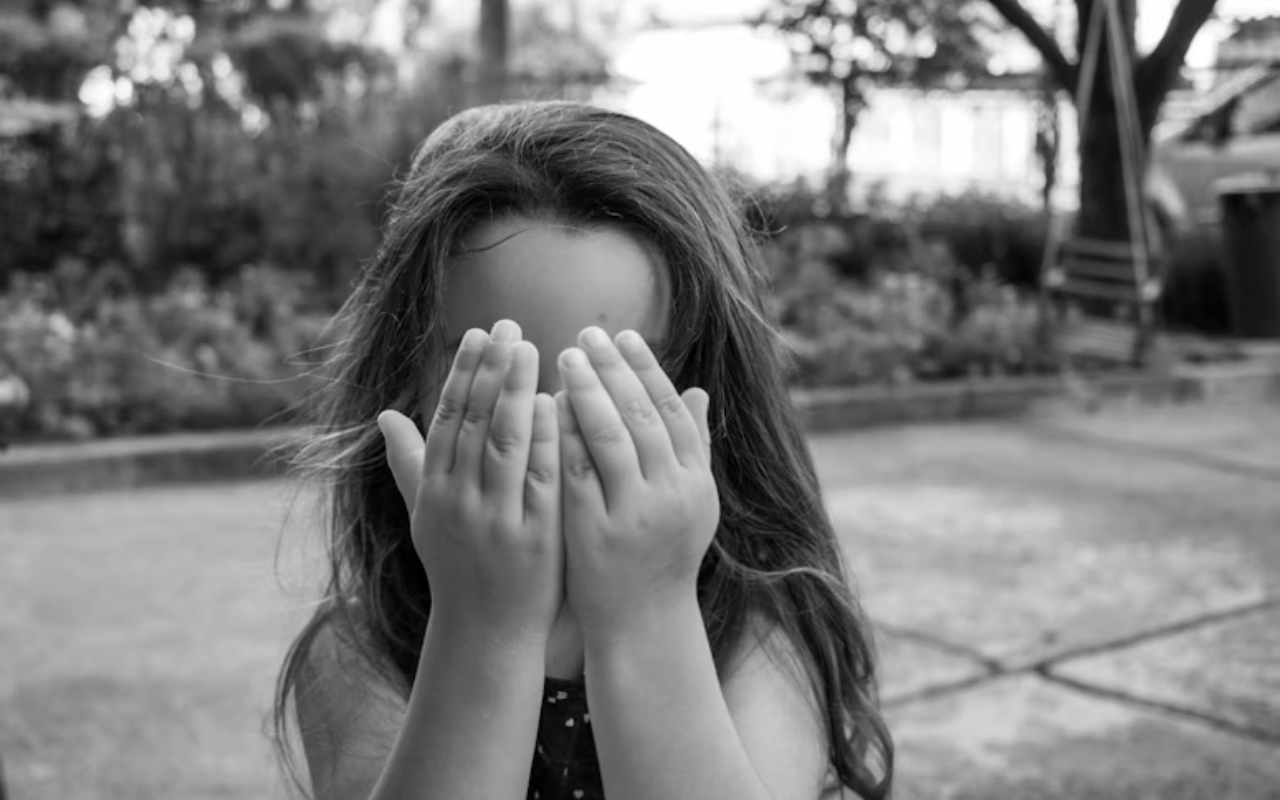 Small female child touching face while playing peek-a-boo