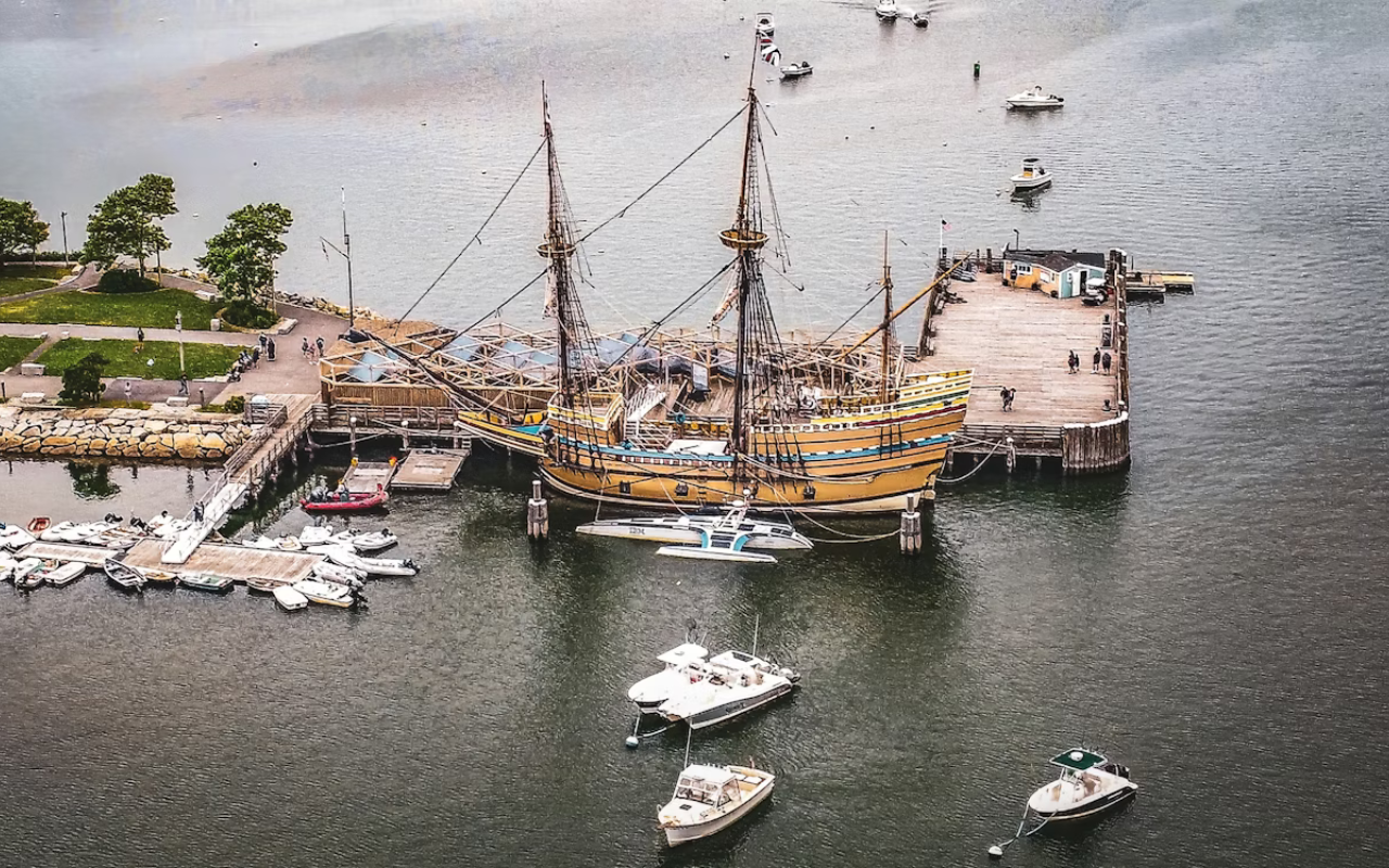Historic Mayflower II ship docked in Plymouth Harbor, a family Thanksgiving travel destination in Massachusetts.