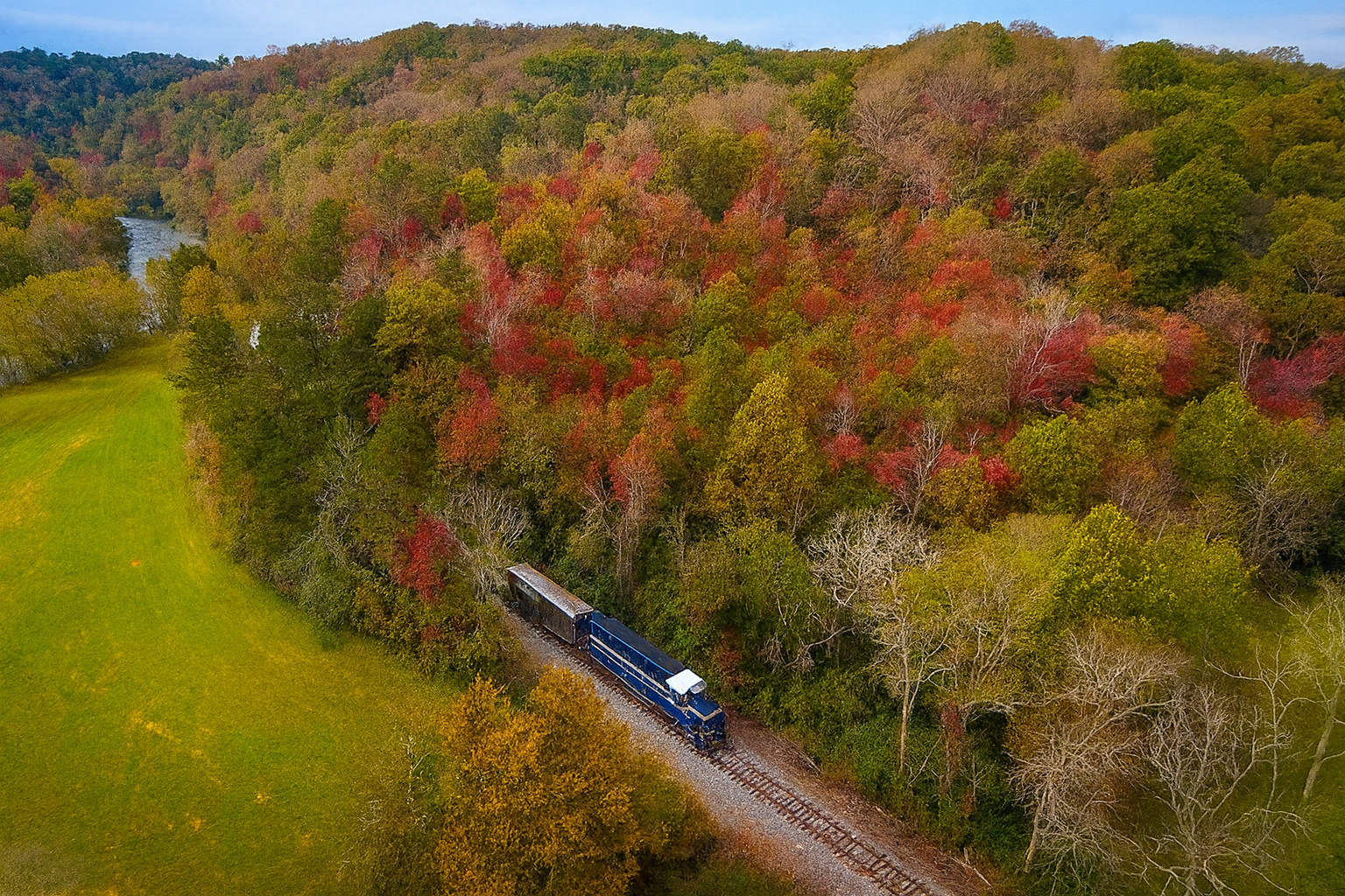 Blue Ridge Scenic Railway train traveling through vibrant autumn foliage along the Toccoa River in Georgia, showcasing colorful fall leaves and scenic mountain views