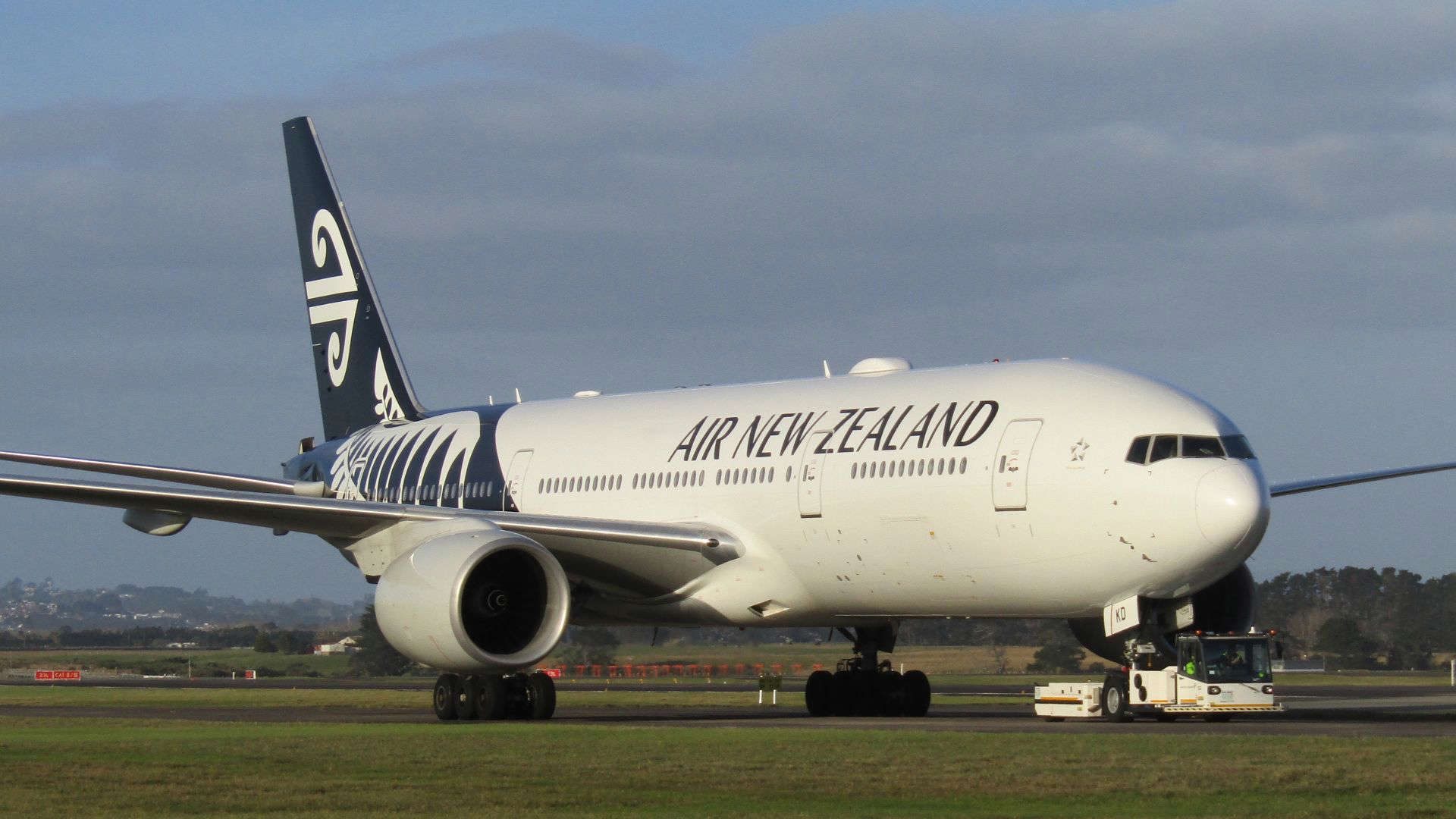 Air New Zealand aircraft on the runway, highlighting the airline’s award-winning cabin crew known for humor, friendliness, and great service.