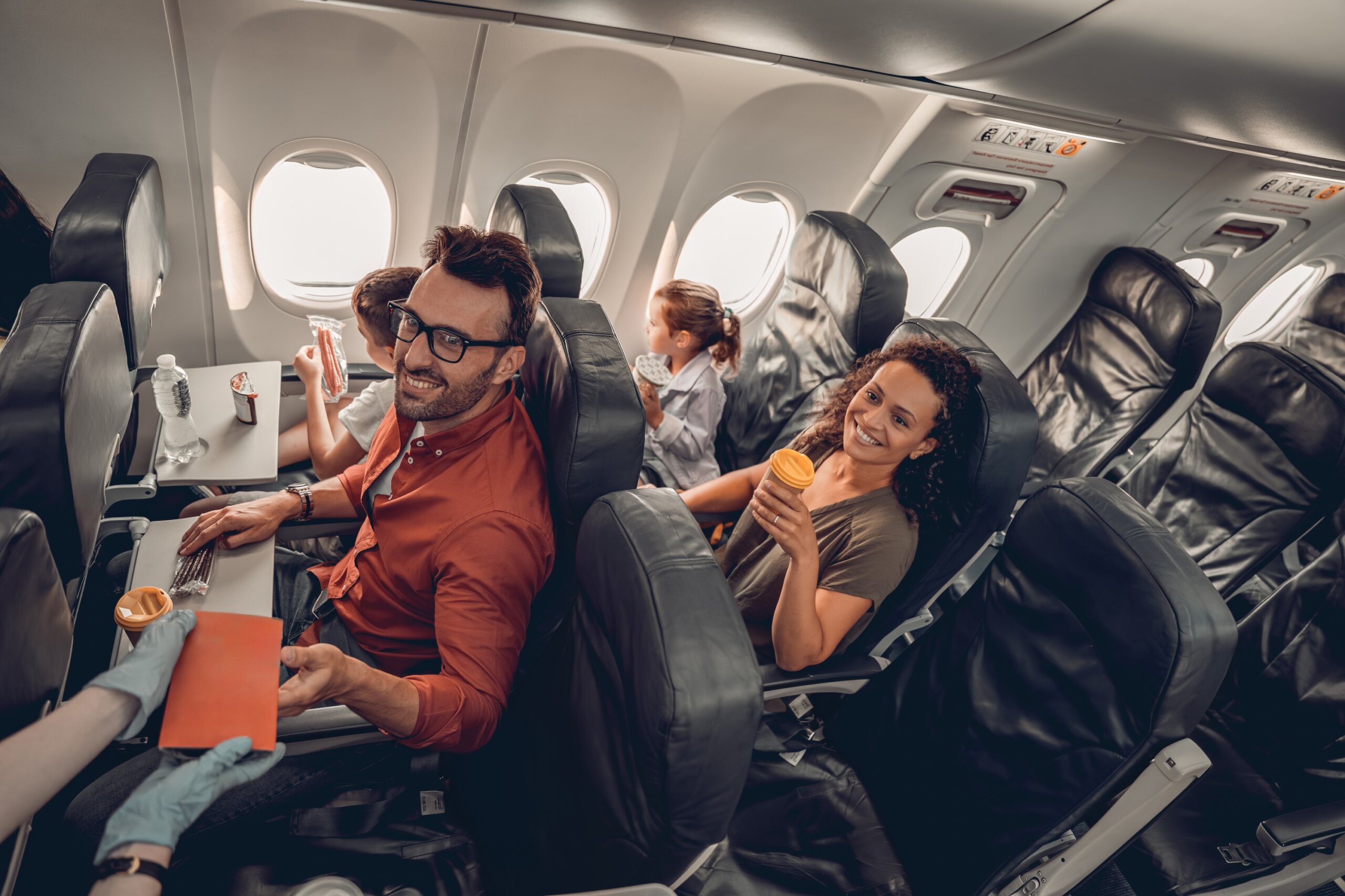 Joyful travelers are happily aboard an airplane, enjoying their flight experience along with tasty refreshments