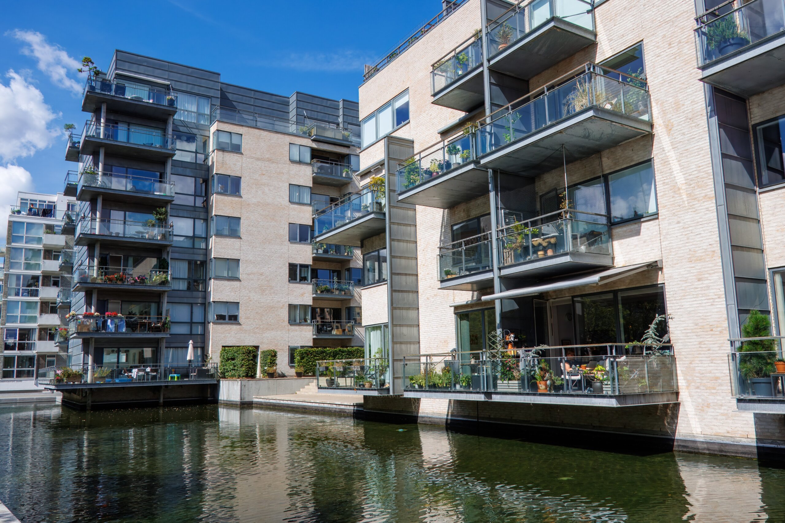 A modern housing estate in Copenhagen, Denmark, featuring water elements that create a cooling microclimate and a sense of immersion in nature, offering residents a sustainable and eco-friendly living