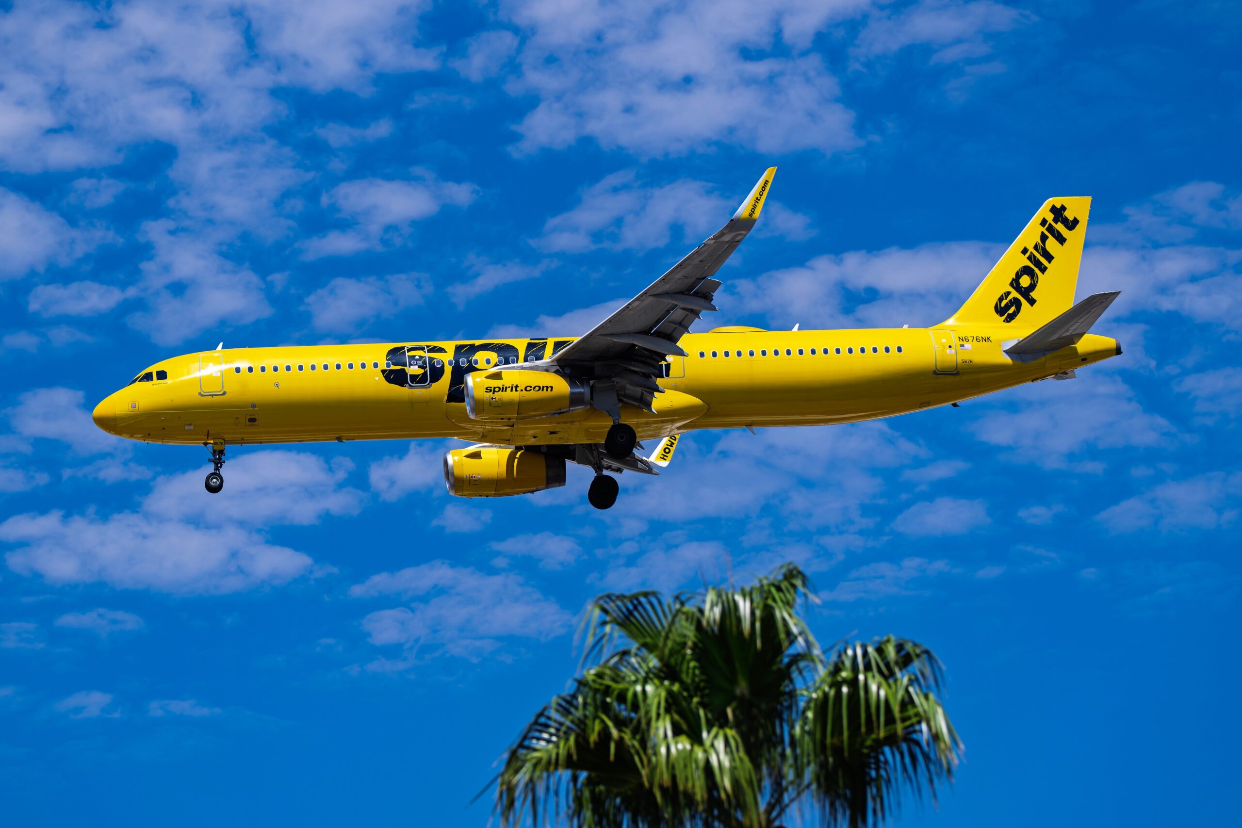 Spirit Airlines yellow plane flying in blue sky budget airline low-cost carrier