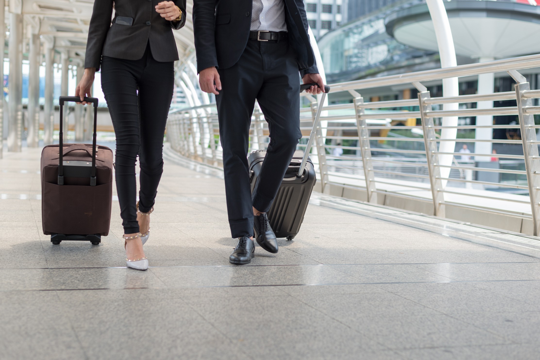 business man and business woman walk together luggage on the public street, business travel