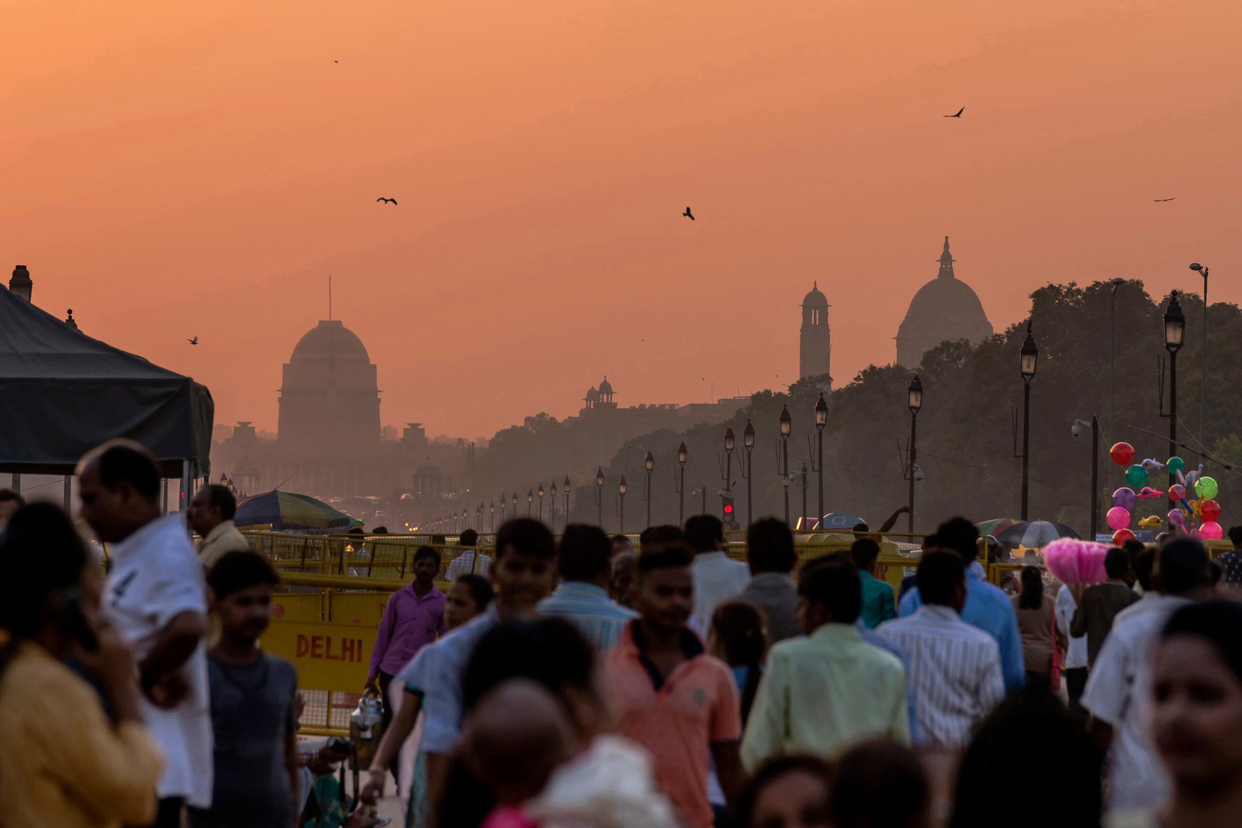 Crowd of people during sunset with government buildings in the background, New Delhi, India