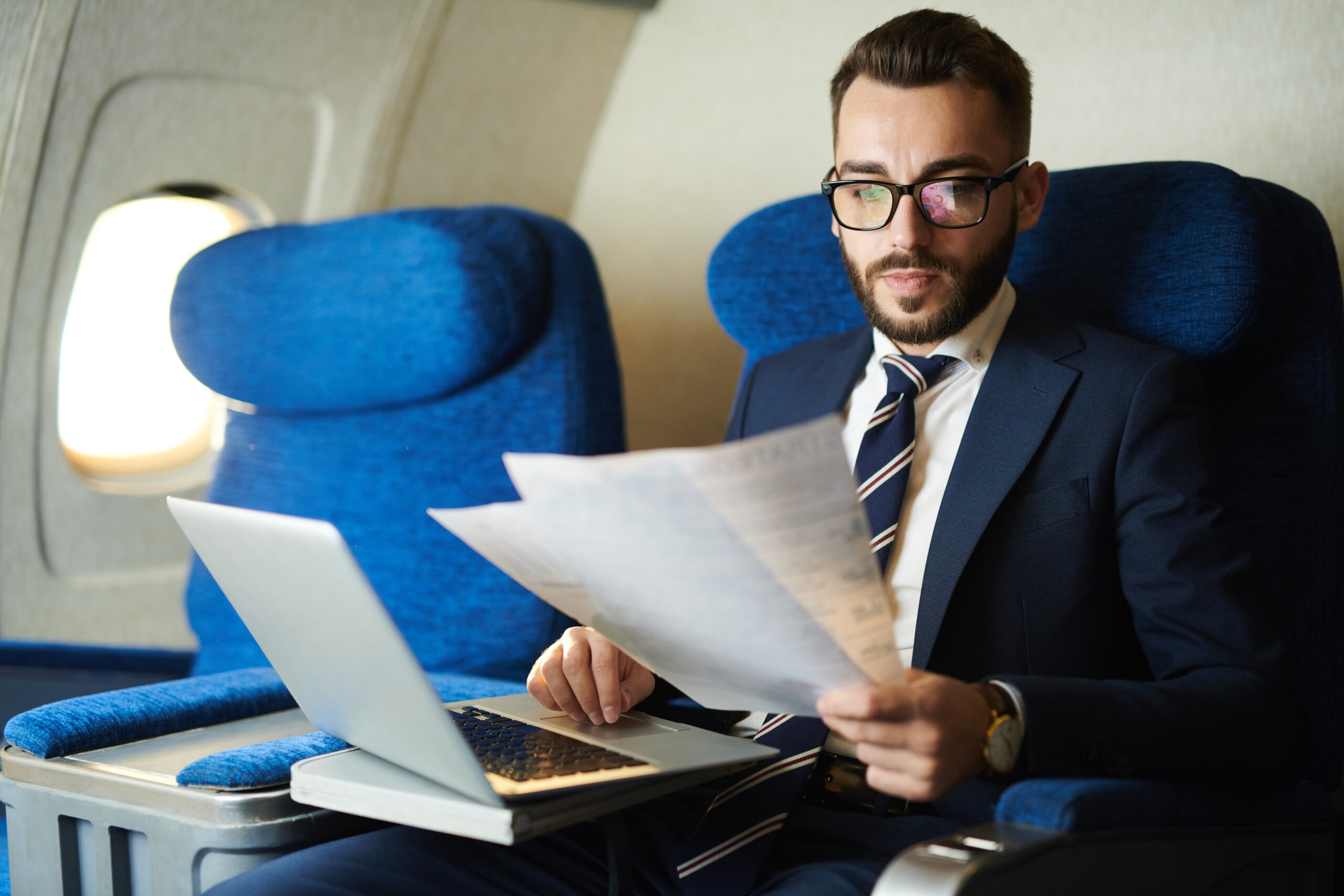 Businessman working comfortably from first class on a standard airplane instead of a budget airline