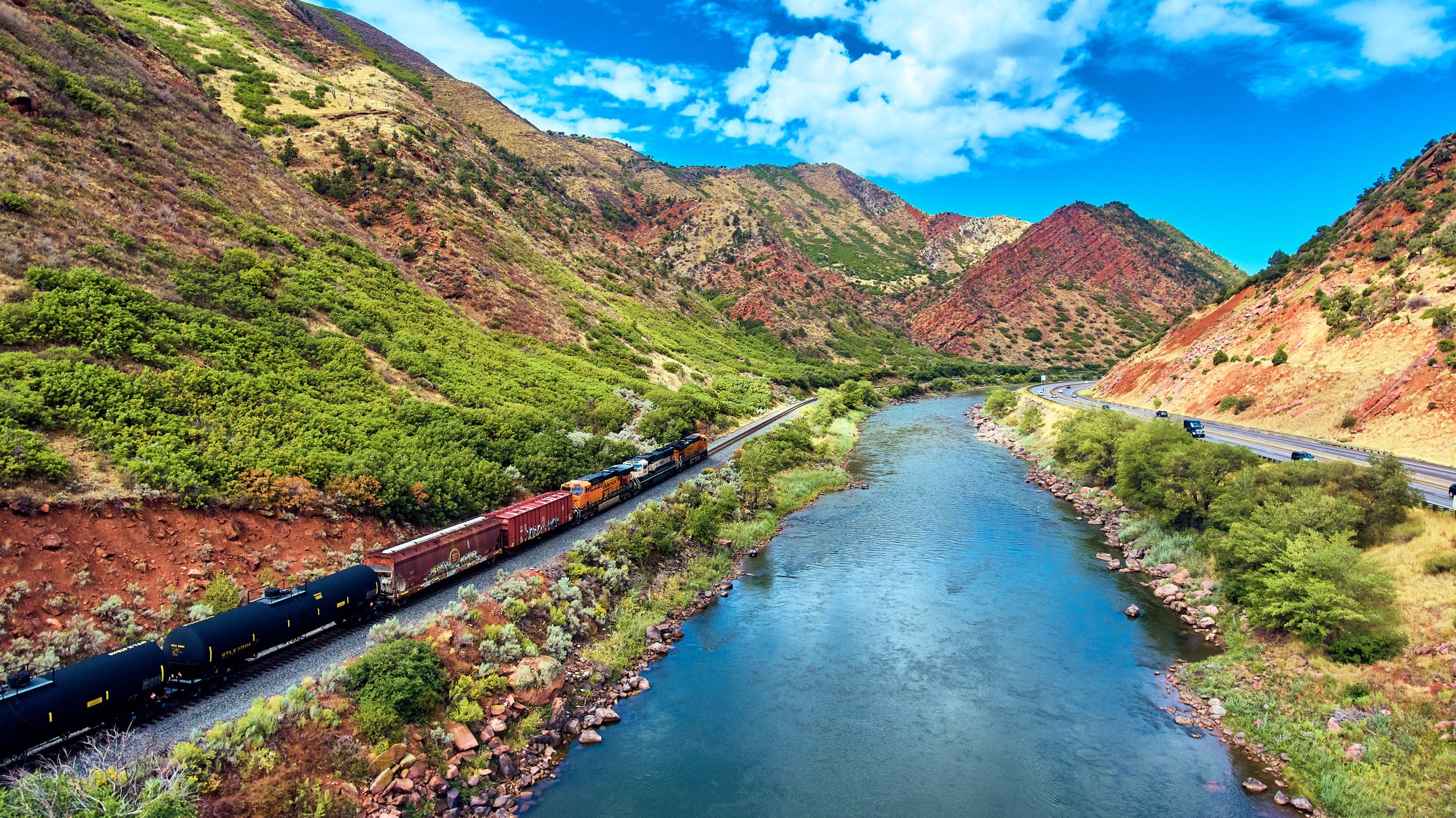 Rocky Mountaineer train traveling beside the Colorado River through red rock canyons on the Rockies to the Red Rocks route.