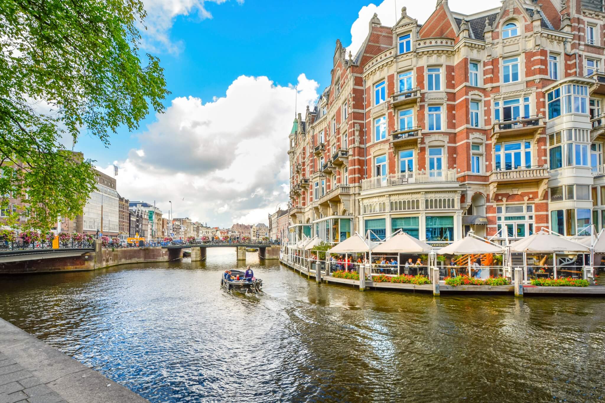 Tourists enjoy a relaxing waterfront lunch at a hotel on one of the major canals near the Museum District in Amsterdam, Netherlands