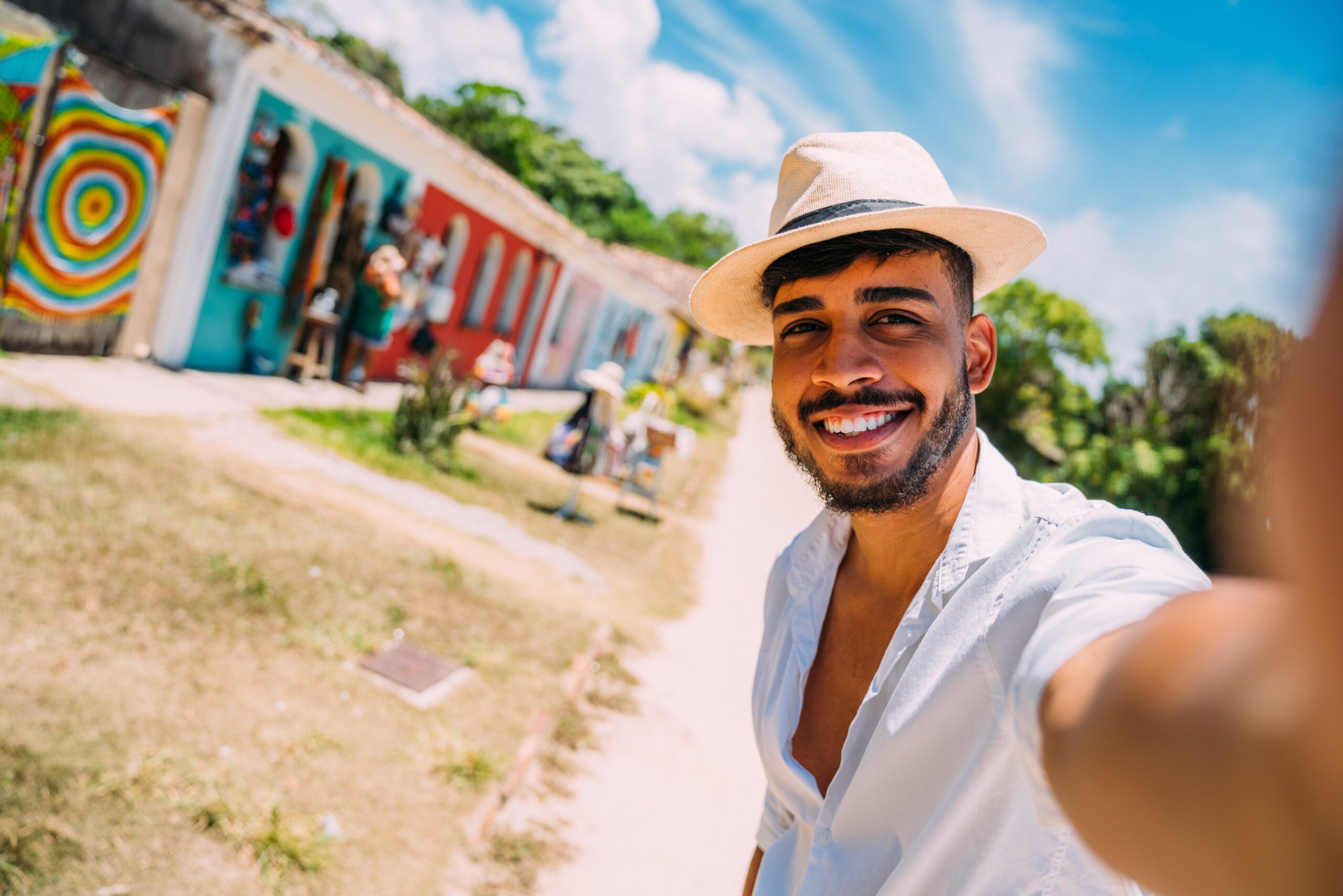 Tourist making selfie in the historic center of Porto Seguro. Latin American man in hat smiling at camera
