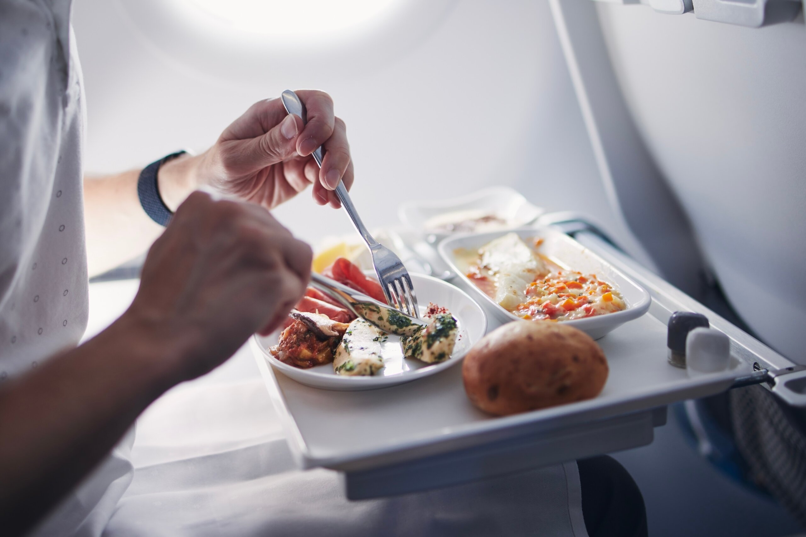Passenger eating airline meal in airplane. Menu in business class on medium haul flight.
