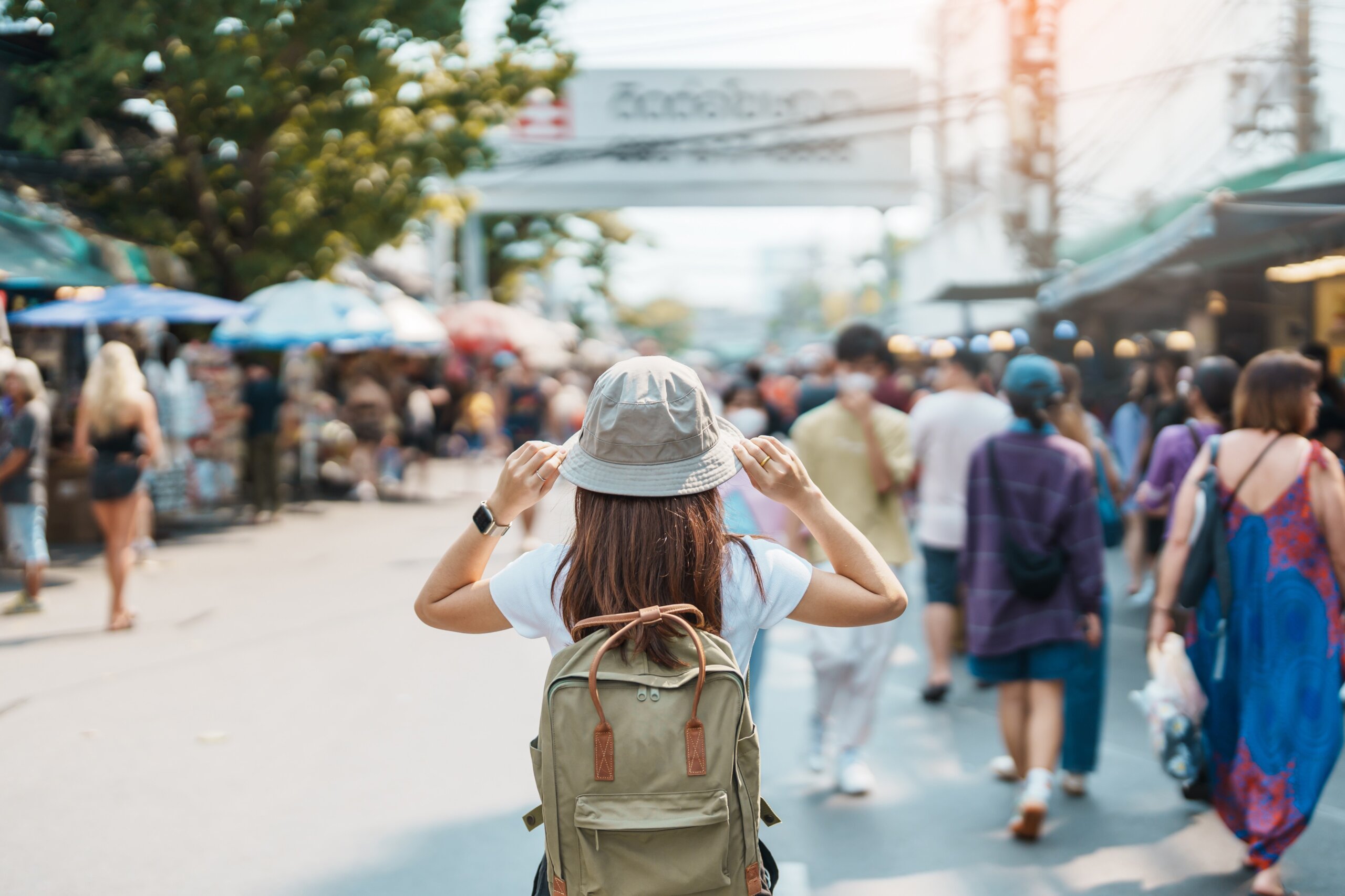 Solo woman traveler visiting in Bangkok, Tourist with backpack and hat sightseeing in Chatuchak Weekend Market, landmark and popular attractions in Bangkok, Thailand. Travel in Southeast Asia concept