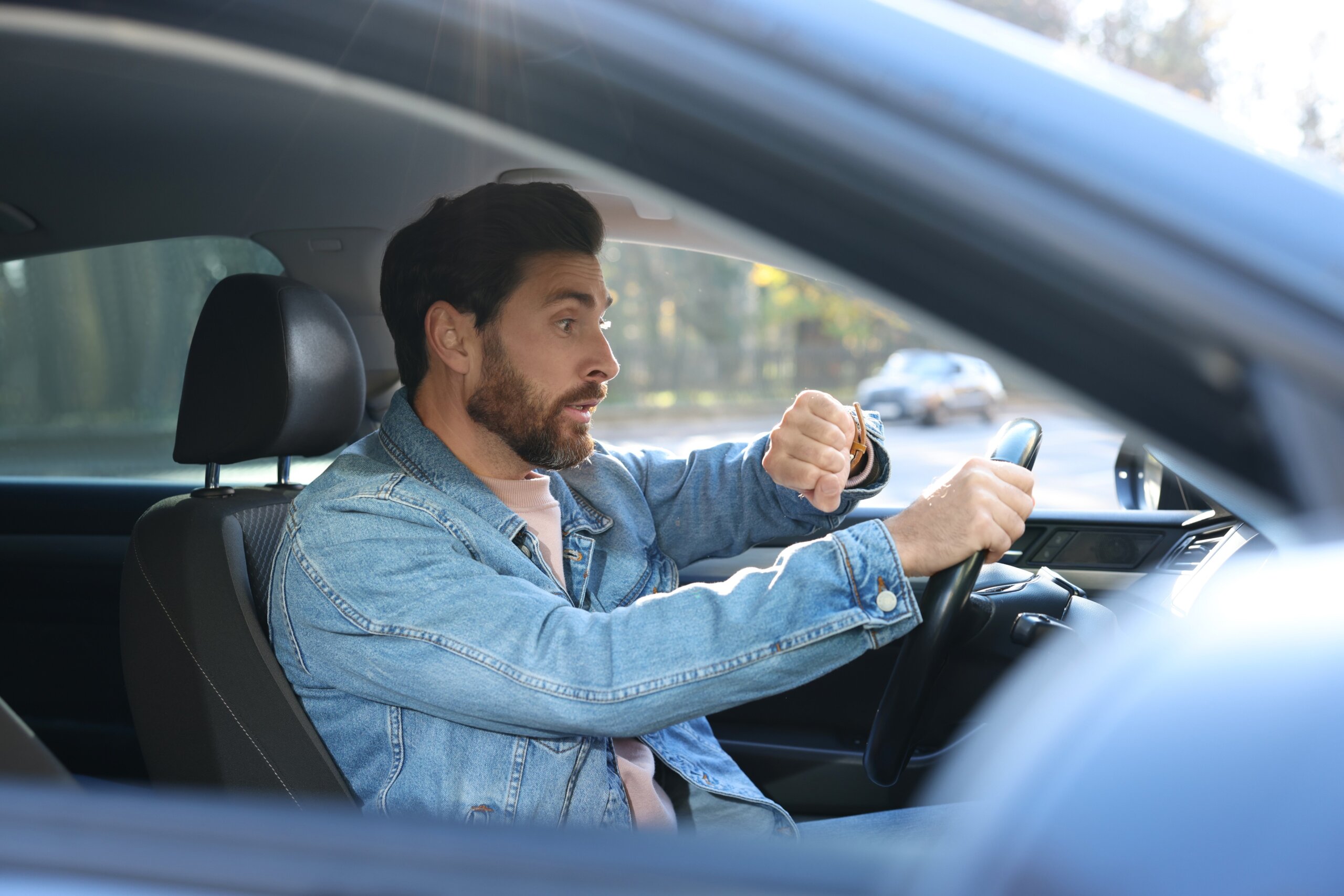 Emotional man checking time on watch in car. Being late concept