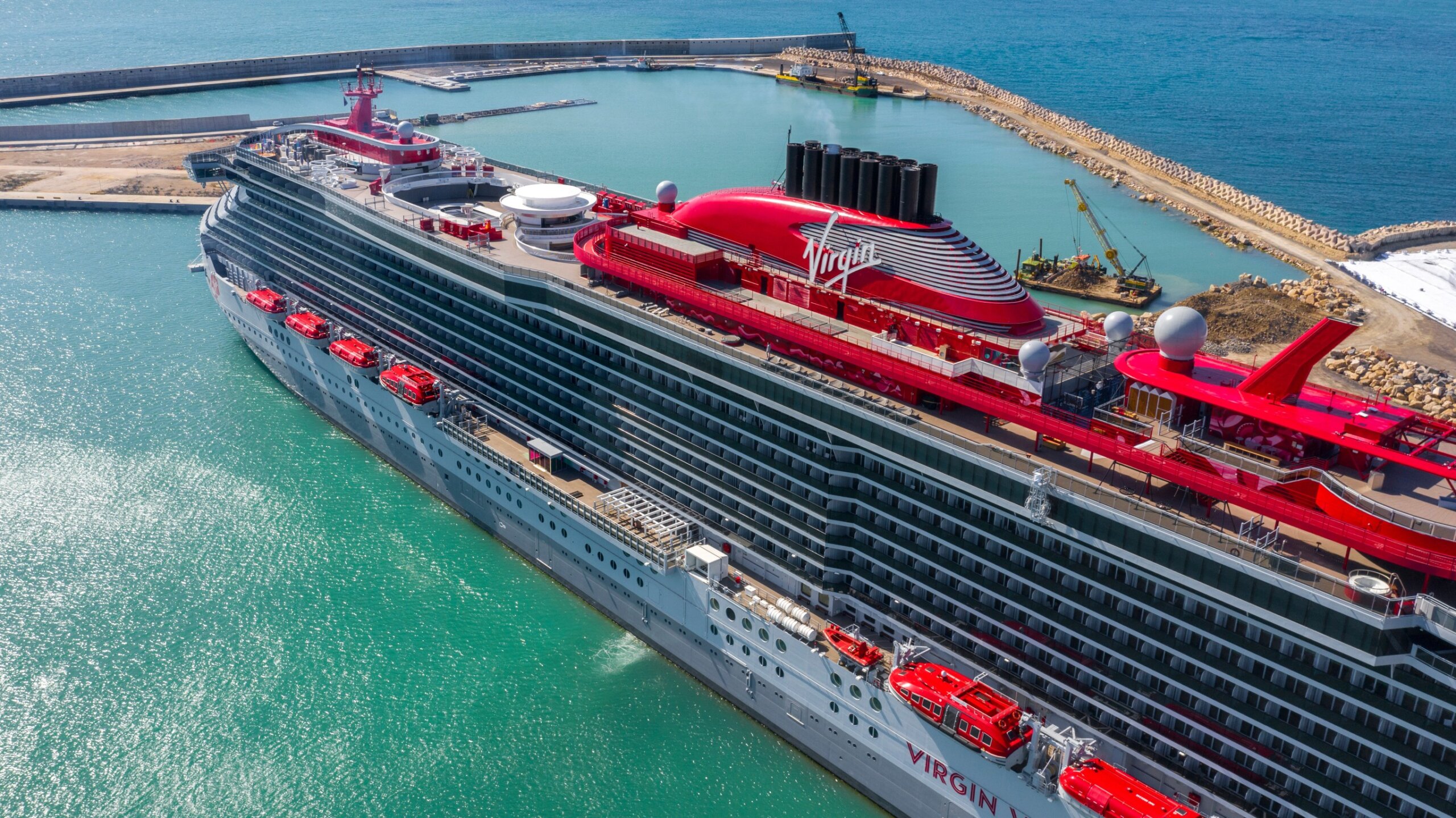 Aerial view of the ship Resilient Lady belonging to the Virgin cruises fleet. The cruise ship is moored in the port near Rome during a beautiful sunny day. Civitavecchia, Italy