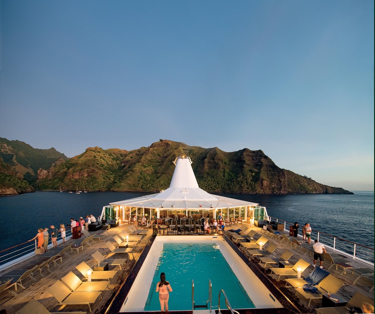 Paul Gauguin Cruises ship in French Polynesia with pool deck and island scenery.