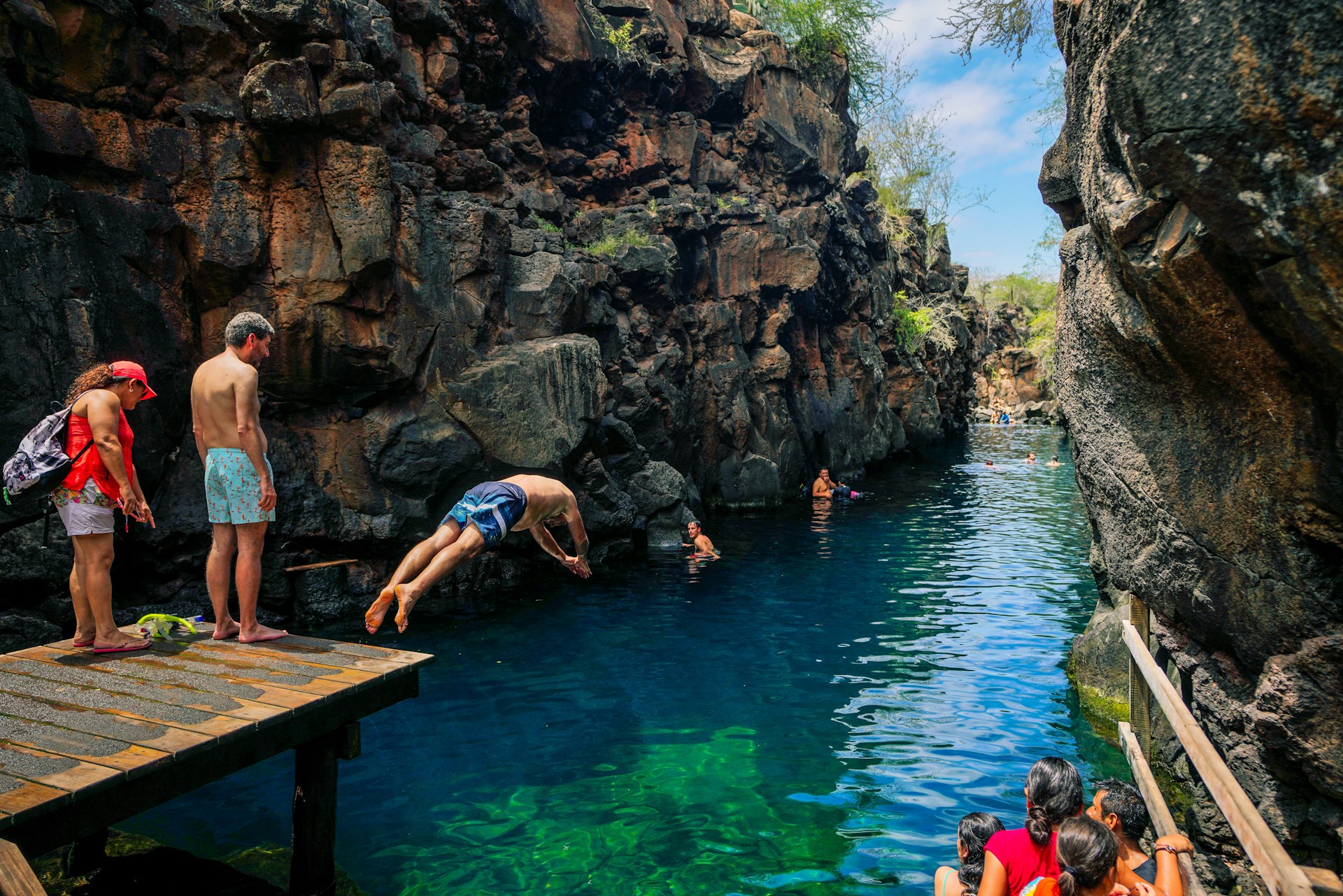 Travelers swimming in a rocky natural pool, representing budget travel in September.