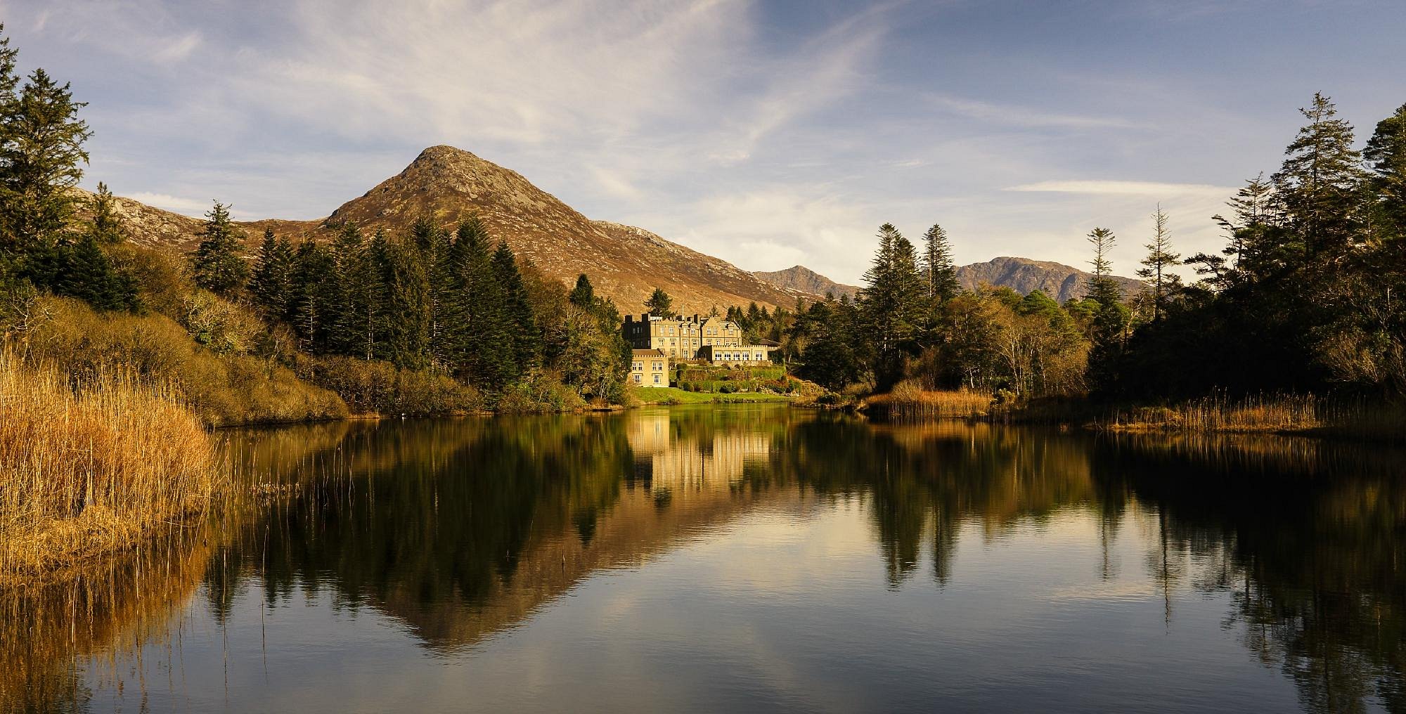 Lough Eske Castle and Donegal landscape reflected in lake during autumn in Ireland.