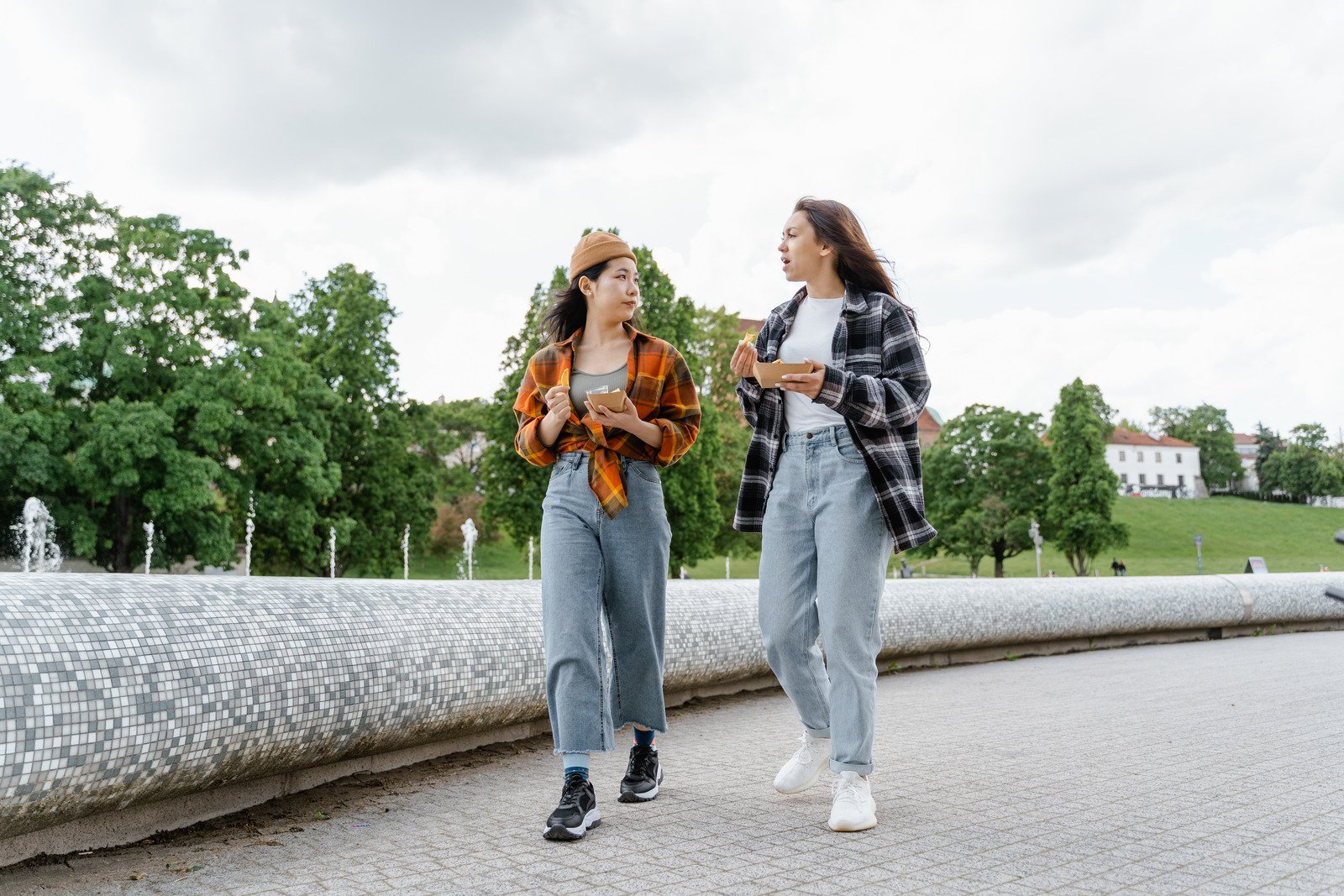 Two women walking and eating near a fountain — illustrating why asking “What else is this country famous for?” can seem dismissive to locals abroad.