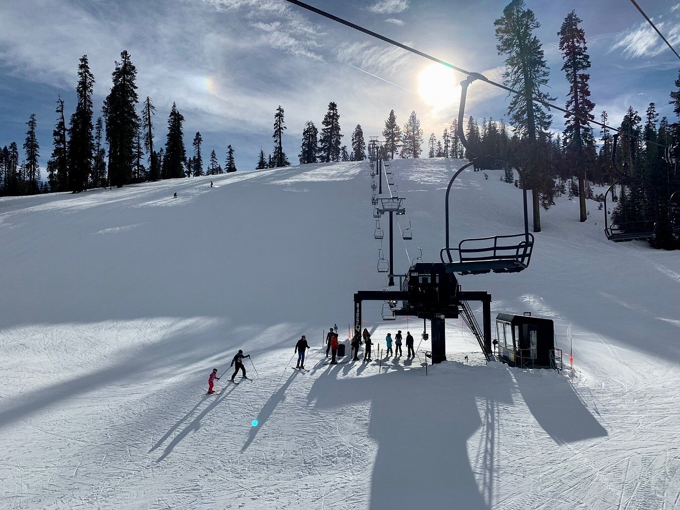 Skiers and snowboarders riding a ski lift at Badger Pass Ski Area in Yosemite National Park on a sunny winter day