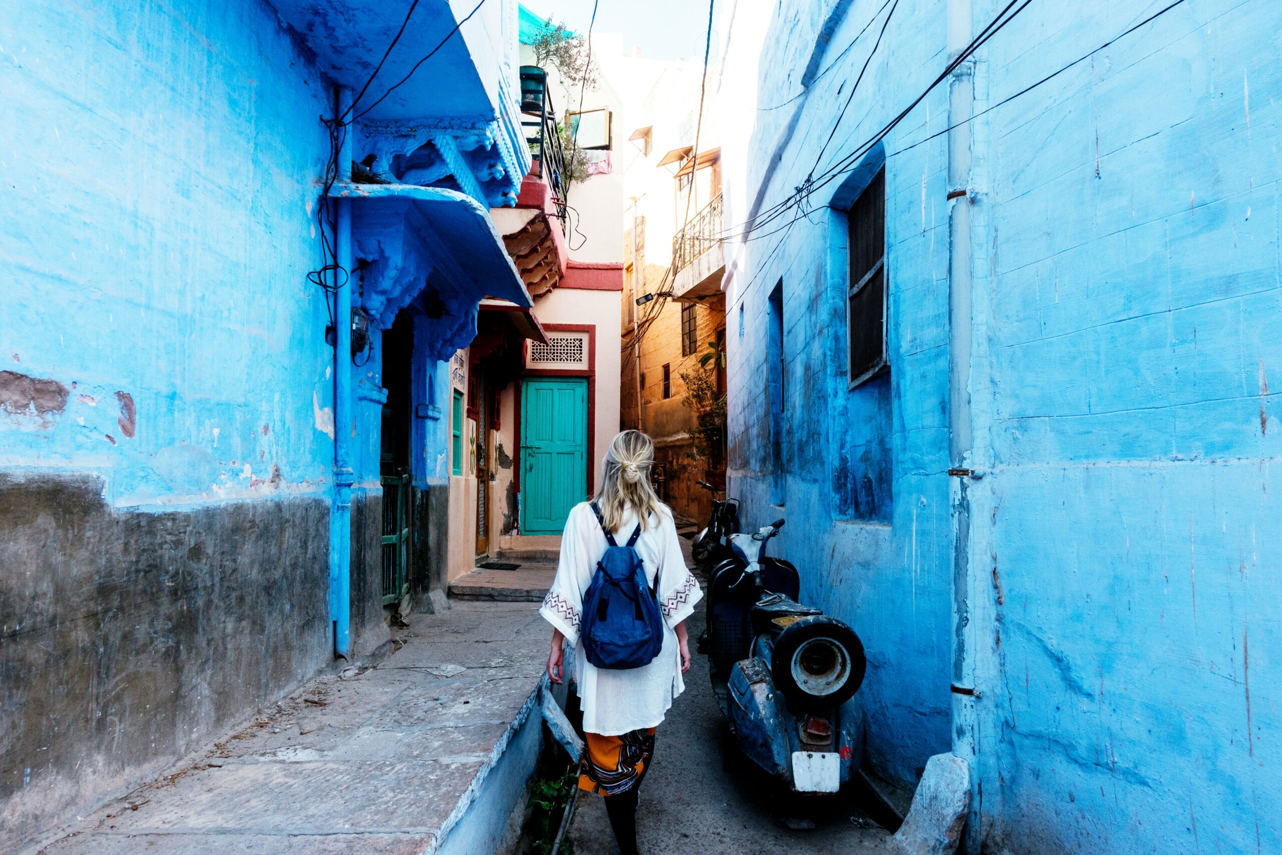 Woman walking through narrow blue streets in India — representing cultural exploration and unforgettable things to do while traveling in India.