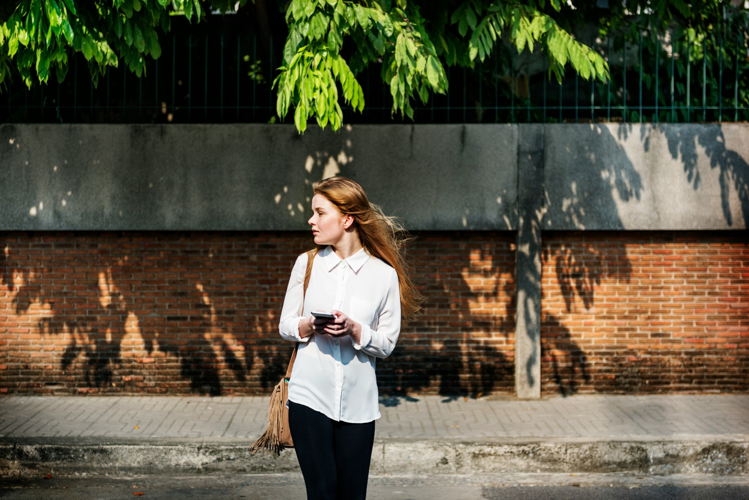 Traveler holding a phone and looking around on a foreign street — representing the phrase “How come nobody speaks English here?” and cultural respect abroad.