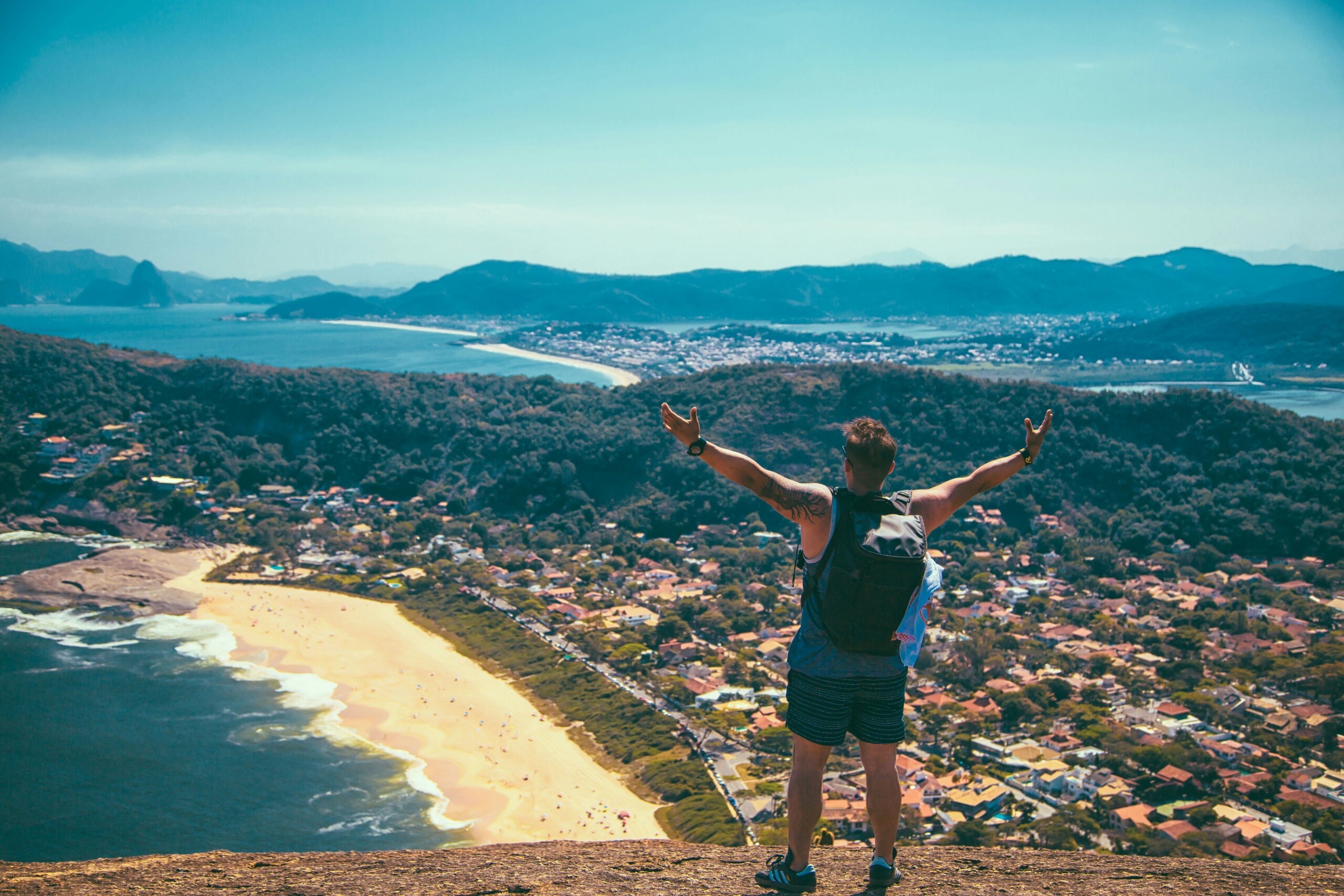 Gen Z traveler standing on a cliff overlooking a coastline, symbolizing spontaneous and budget-friendly travel trends.