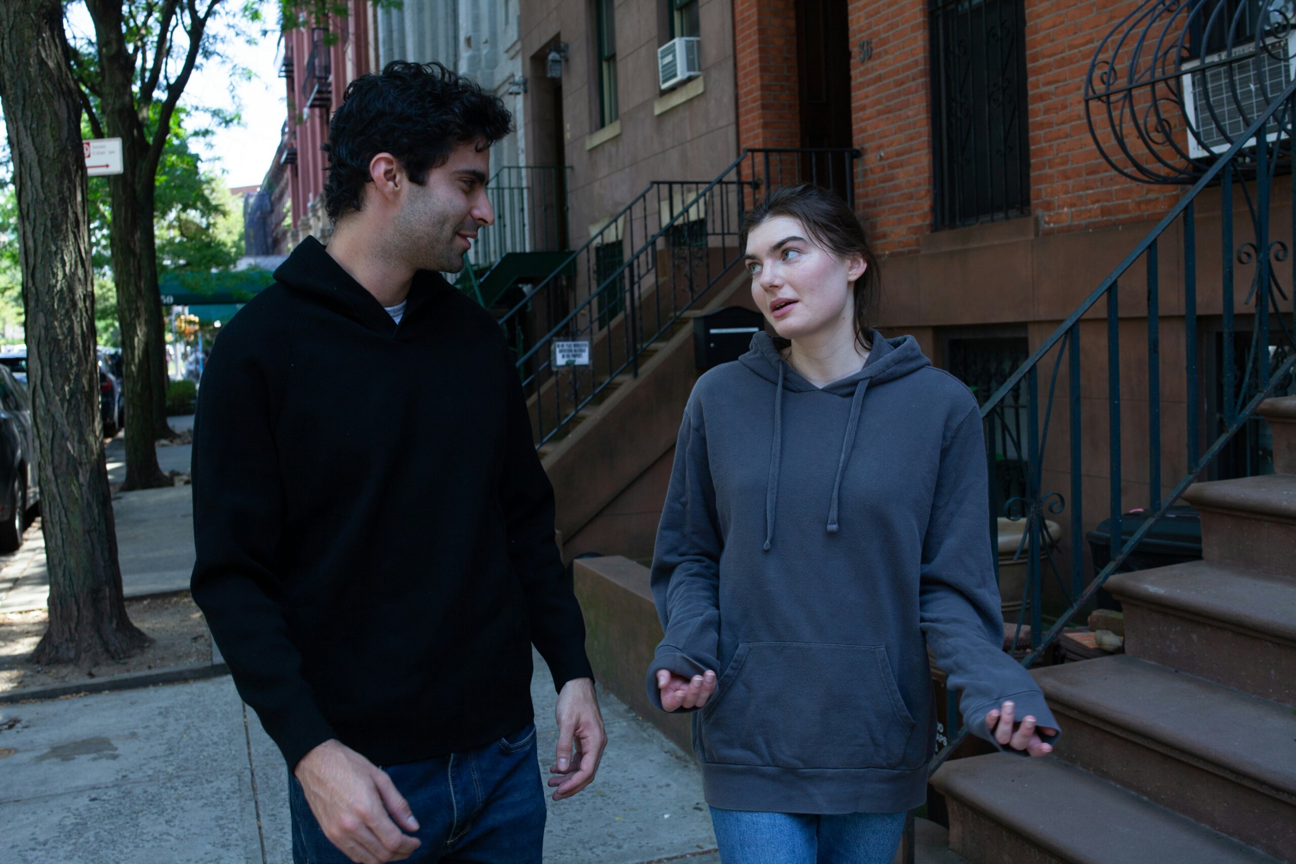 Man and woman talking on a city sidewalk — representing the phrase “We’d handle it differently in America” and how constant comparisons can offend locals abroad.