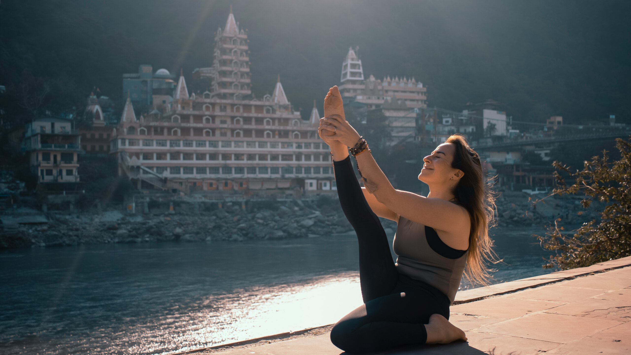 Woman practicing yoga by the Ganges River in Rishikesh, the Yoga Capital of the World — a peaceful spiritual destination in India.