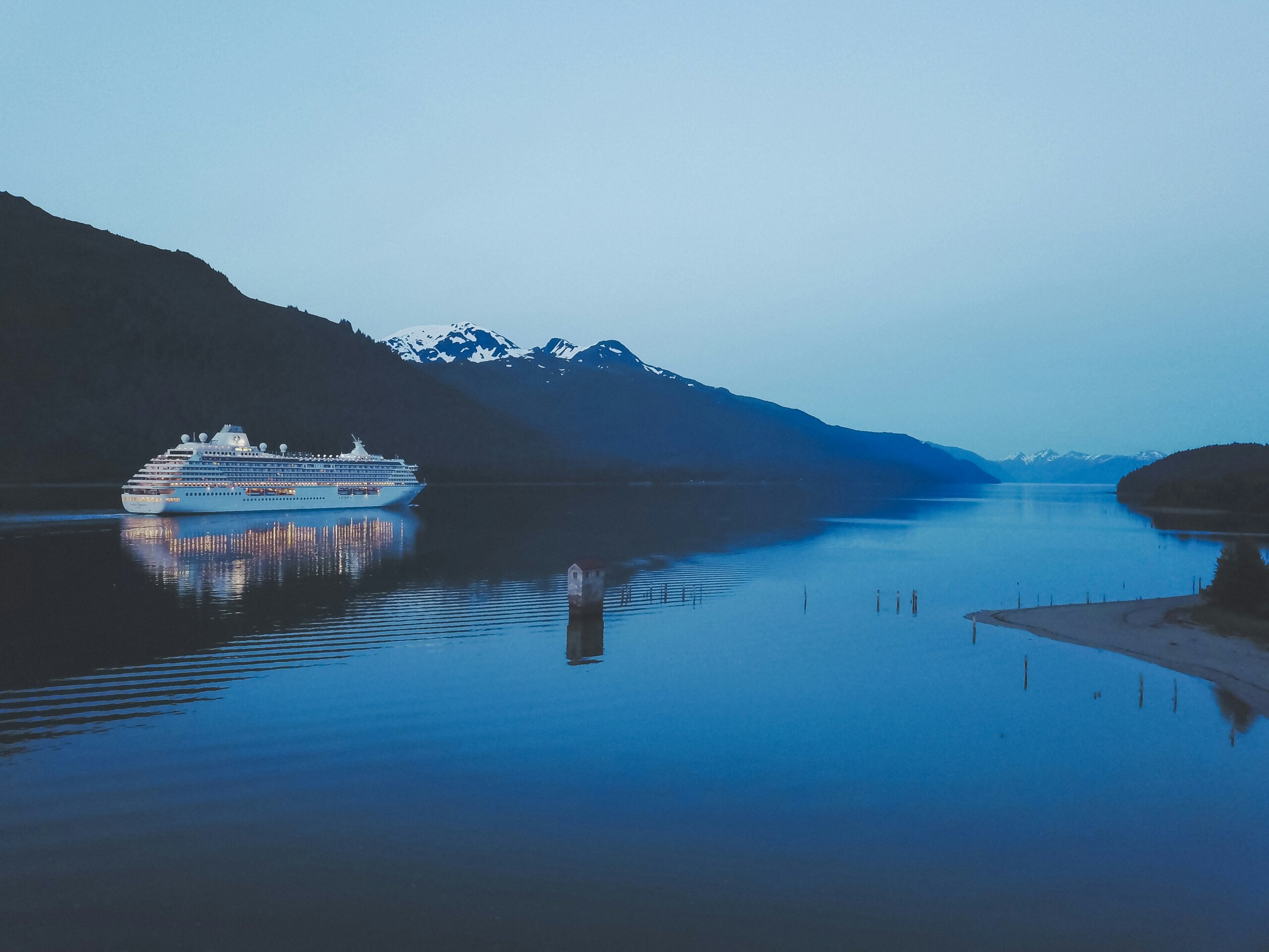 River cruise ship on calm blue waters with mountain views, representing domestic vs. European river cruises.