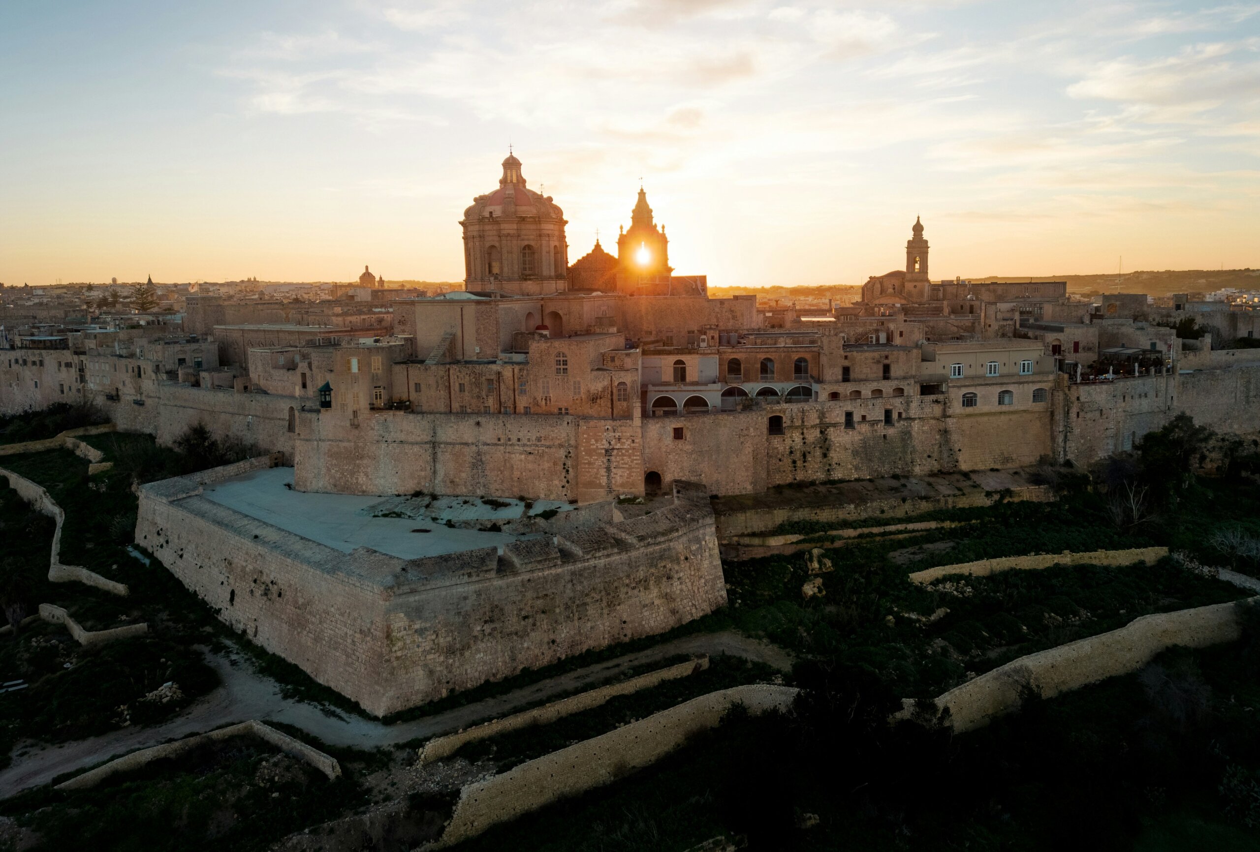 Sunset over fortified Mediterranean Old Town in Malta with stone walls, churches, and sea views