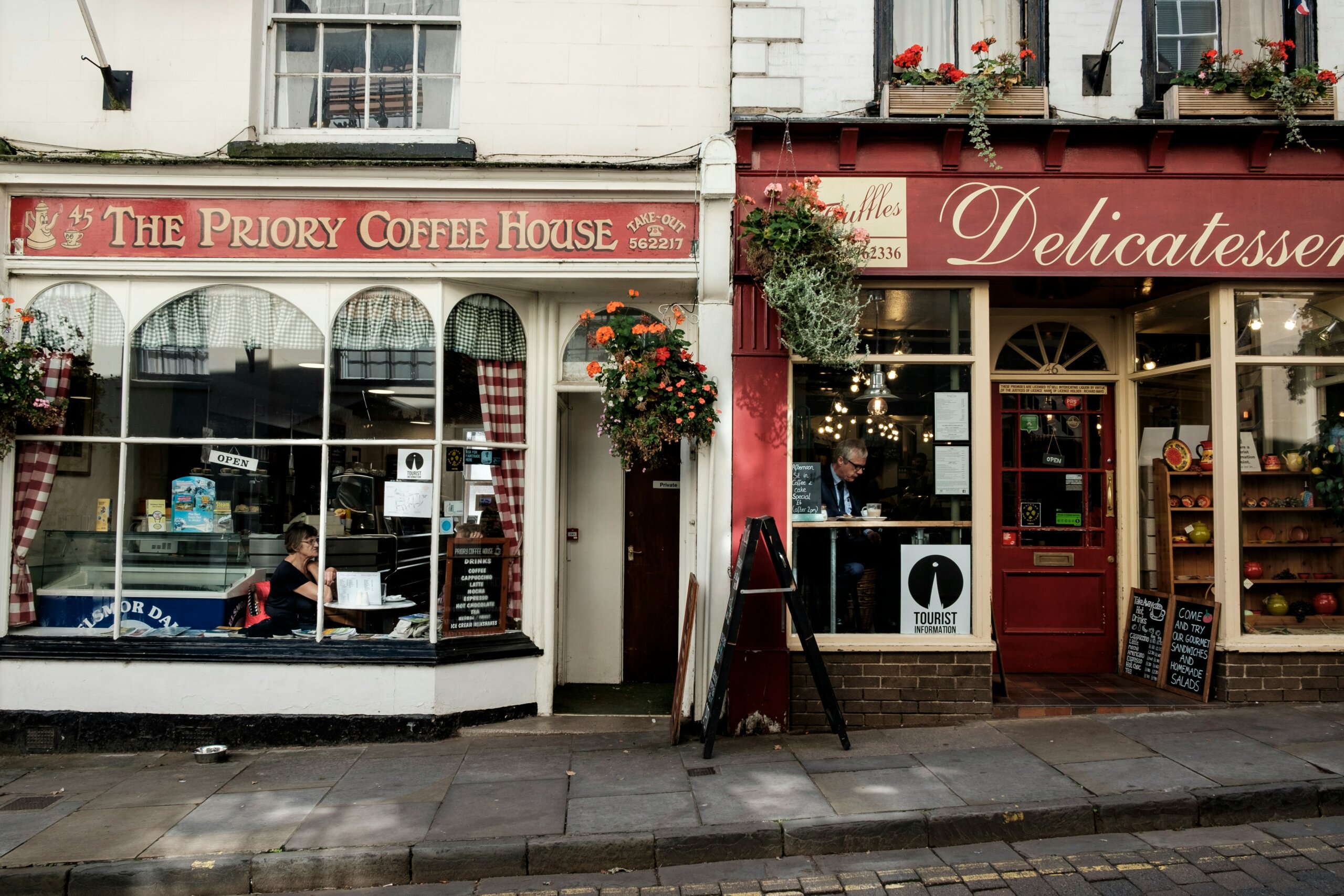 Street view of a cozy coffee house and delicatessen in a small town, capturing the charm of small town escapes and hidden travel destinations