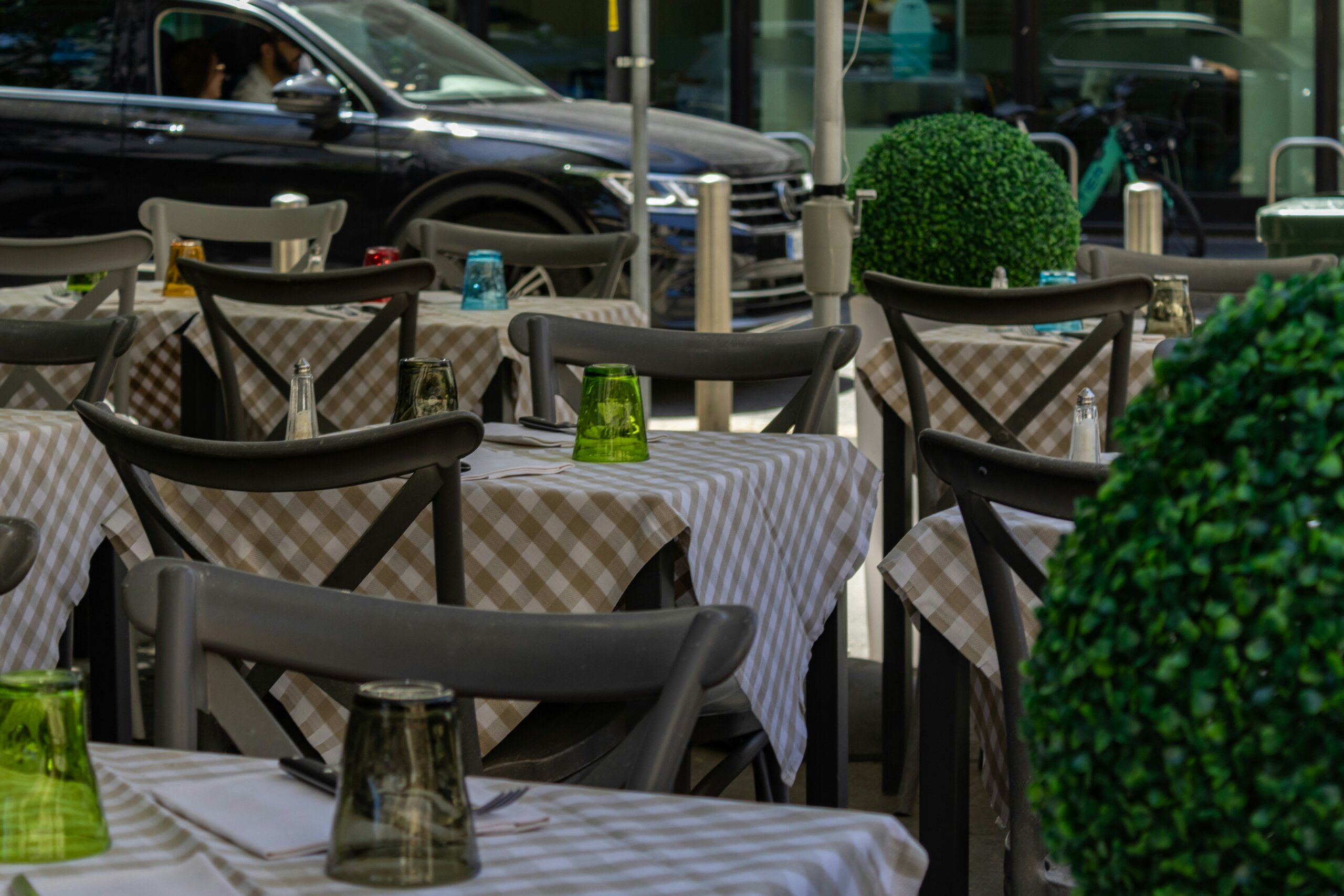 Outdoor Italian café with checkered tablecloths and glassware, highlighting table service culture.