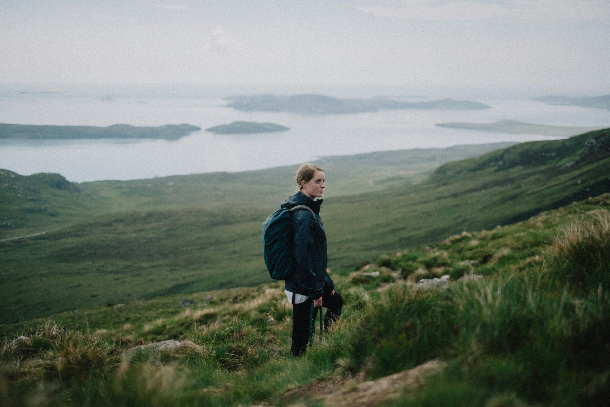 Hiker overlooking Scotland’s Highlands with lochs and rolling hills in the distance, symbolizing famous landmarks and secret corners.