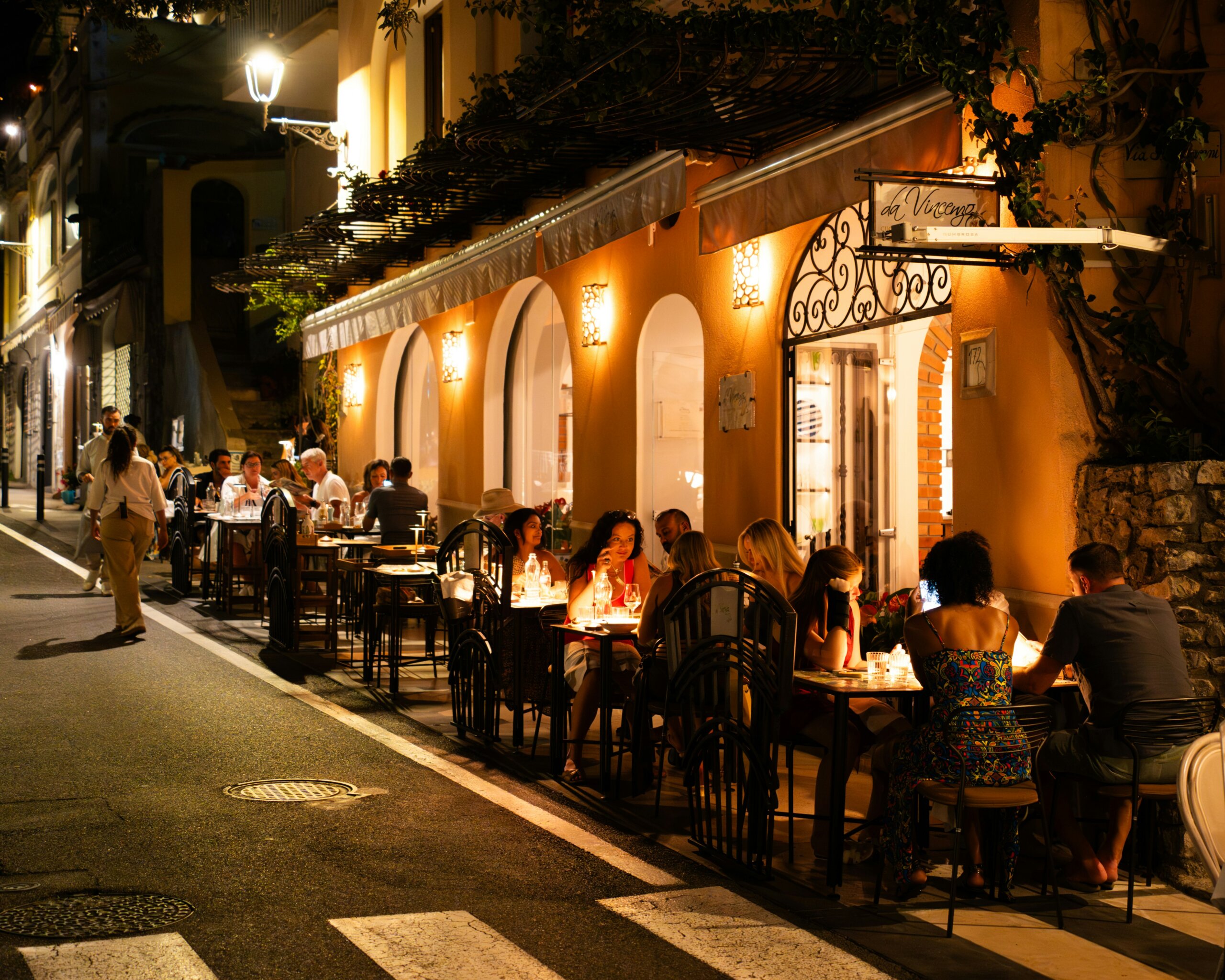 Tourists and locals enjoying dinner at an Italian street restaurant, showcasing authentic dining traditions and food culture in Italy.