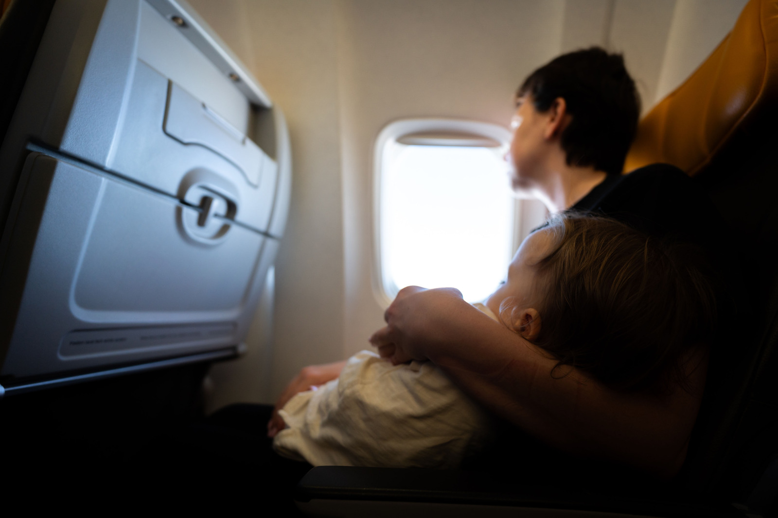 Passenger holding baby on airplane seat, highlighting bad airplane etiquette like giving flight attendants dirty diapers to handle — one of the polite habits flight attendants secretly hate.