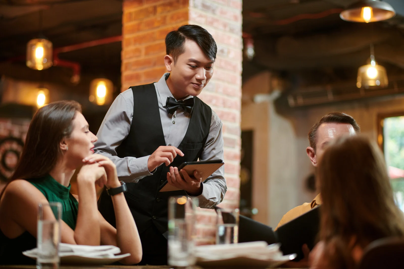 Waiter taking an order at a restaurant table — showing why saying “Could you speed it up?” to service staff can be seen as rude while traveling abroad.