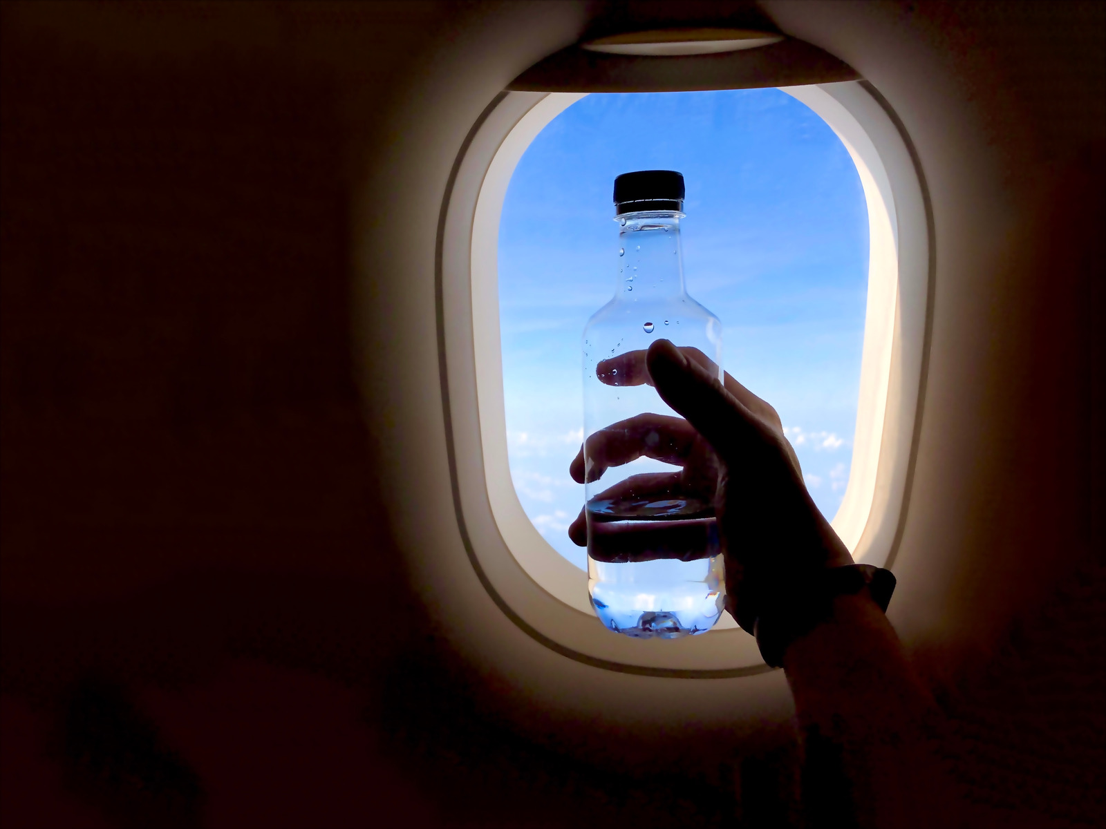 "Airplane passenger putting luggage in overhead bin — one of the polite habits flight attendants secretly hate as part of bad airplane etiquette.