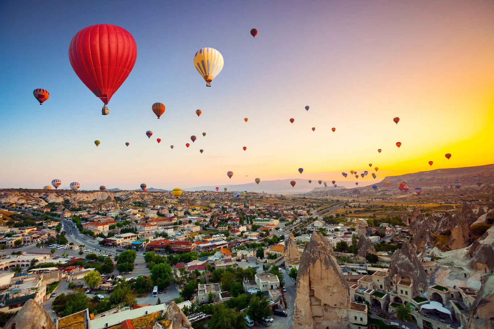 Hot air balloons floating over Cappadocia’s unique rock formations at sunrise in Turkey.