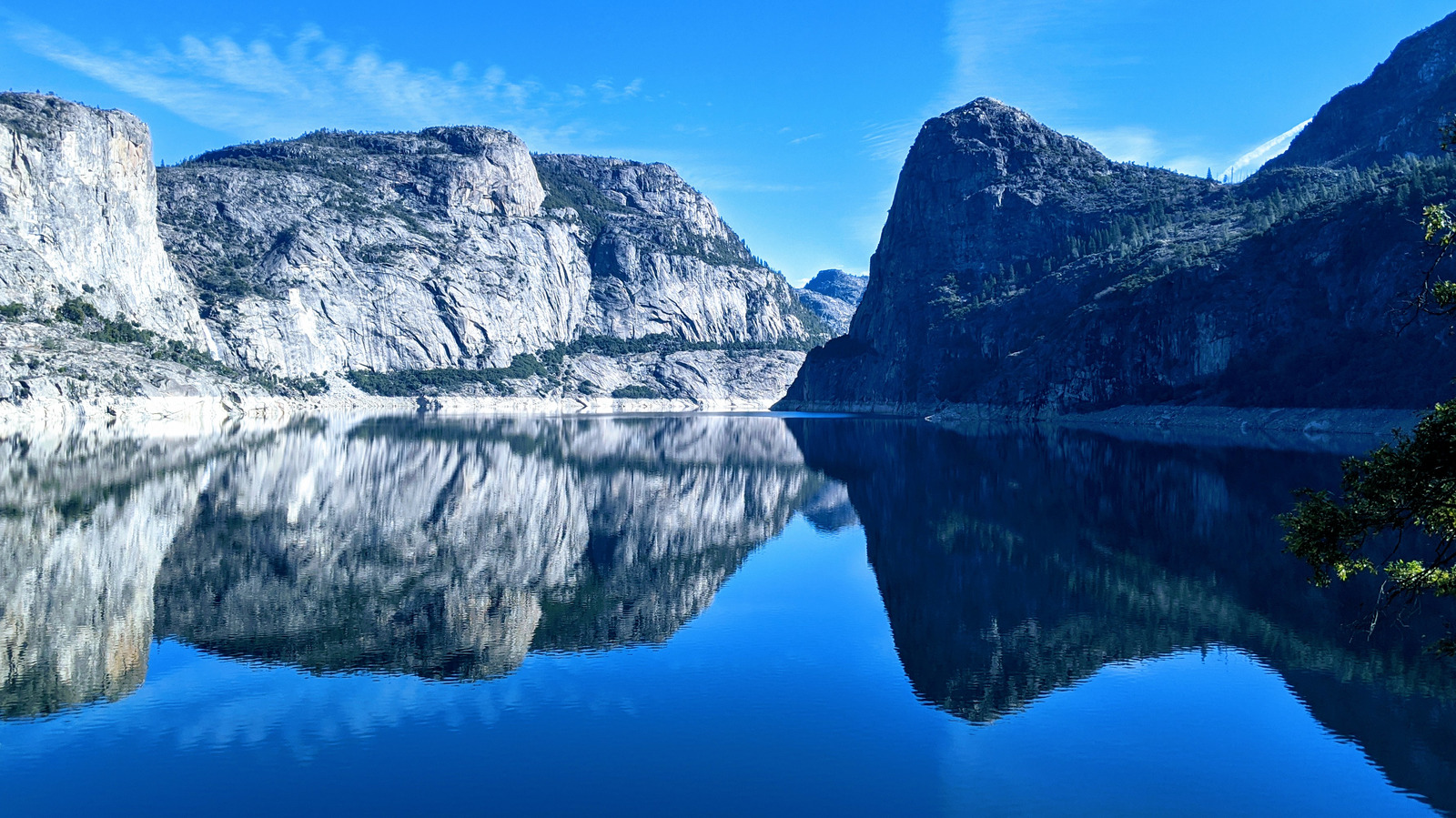 Granite cliffs reflecting in the calm blue reservoir at Hetch Hetchy in Yosemite National Park