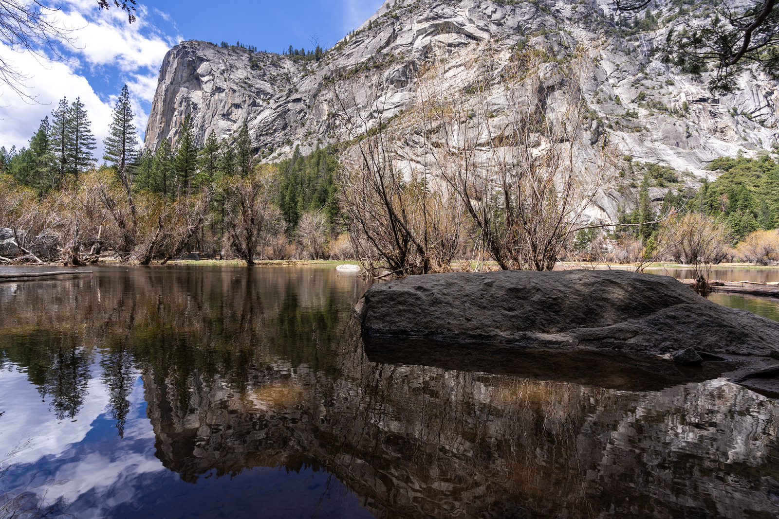 Reflection of Half Dome in Mirror Lake surrounded by trees and granite cliffs in Yosemite National Park